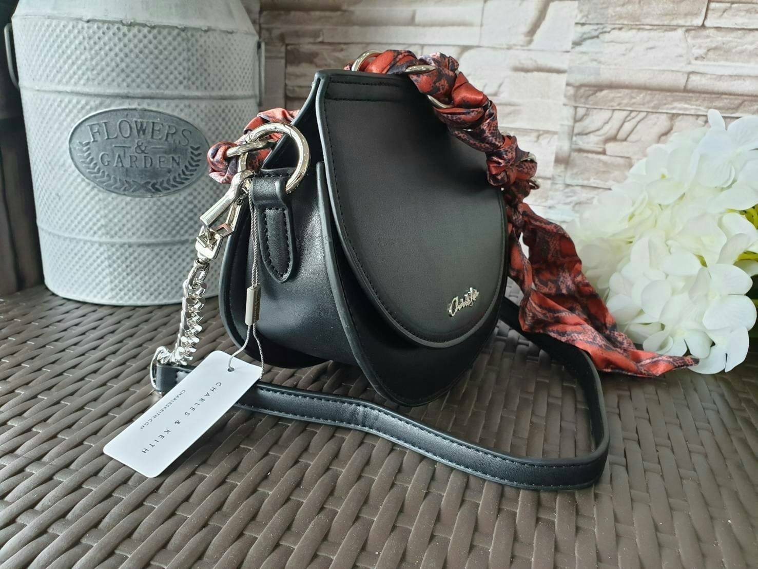 CHARLES & KEITH รุ่น LEATHER SATIN SCARF CROSSBODY BAG SL2-50150828 ราคาปกติช้อป ( ฿3,590.00 ) กระเป๋าถือ และ สะพาย ทรงโค้งมน หนังเรียบ ตั้งอยู่ทรง ด้านหน้าติดโลโก้แบรนด์ อะไหล่เงิน หูจับสายกระเป๋าร้อยเข้ากับห่วงเหล็กกลมๆ ด้วยผ้าลายสวยงามผูกเป็นโบว์เก๋ๆ ถ