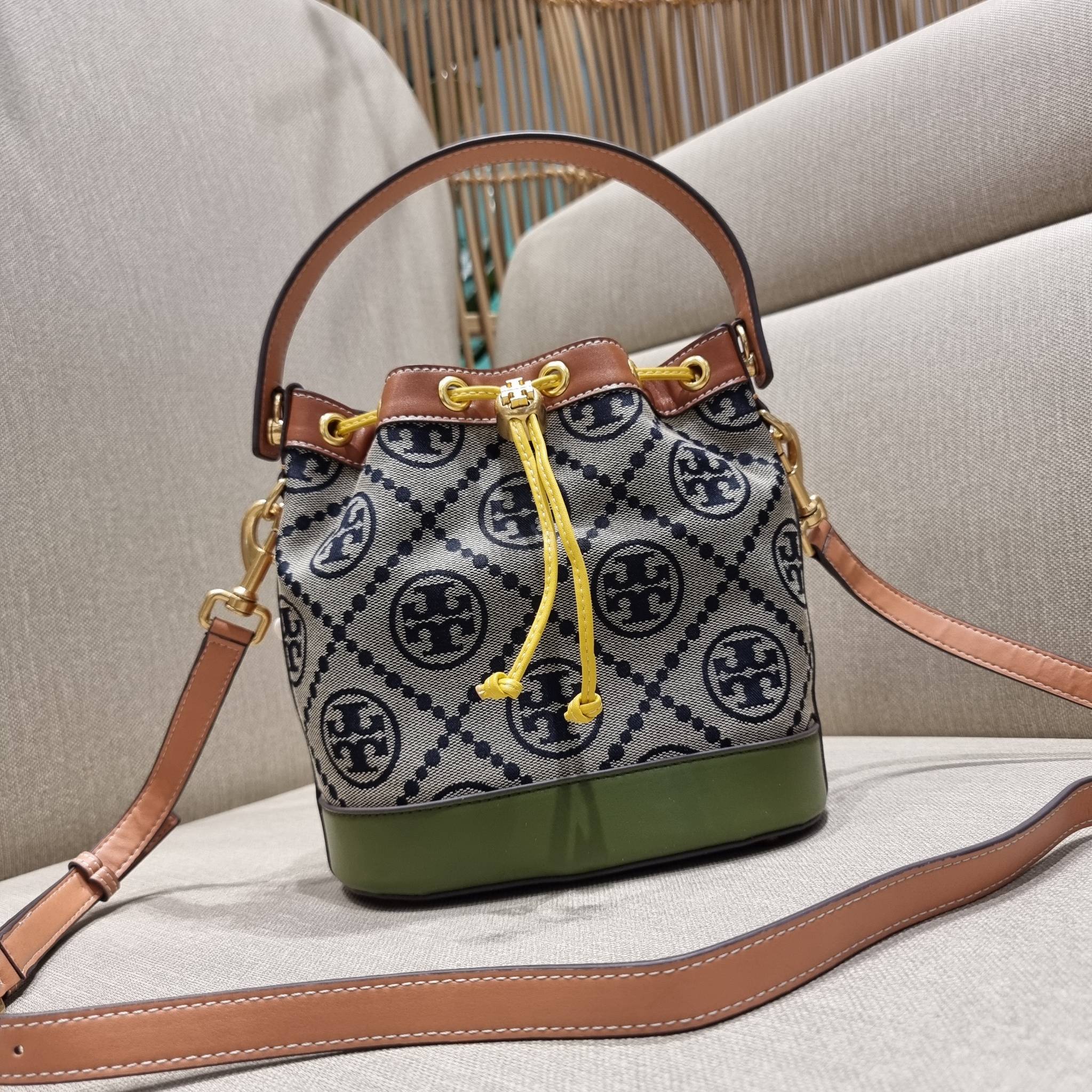 TORY BURCH T MONOGRAM COLORBLOCK JACQUARD BUCKET BAG ไอเท็มใหม่ที่ใครๆก็รอ กระเป๋าบัคเก็ตทรงสวย ที่ยังคงให้ความโดดเด่นด้วยลวดลายเอกลักษณ์ เพิ่มเติมดีไซน์บล็อคสี ตัดกันได้อย่างลงตัว ถักทอบนวัสดุ woven jacquard ลายคมชัด สลับส่วนของหนังแท้ ภายในเป็นช่องโล่งก