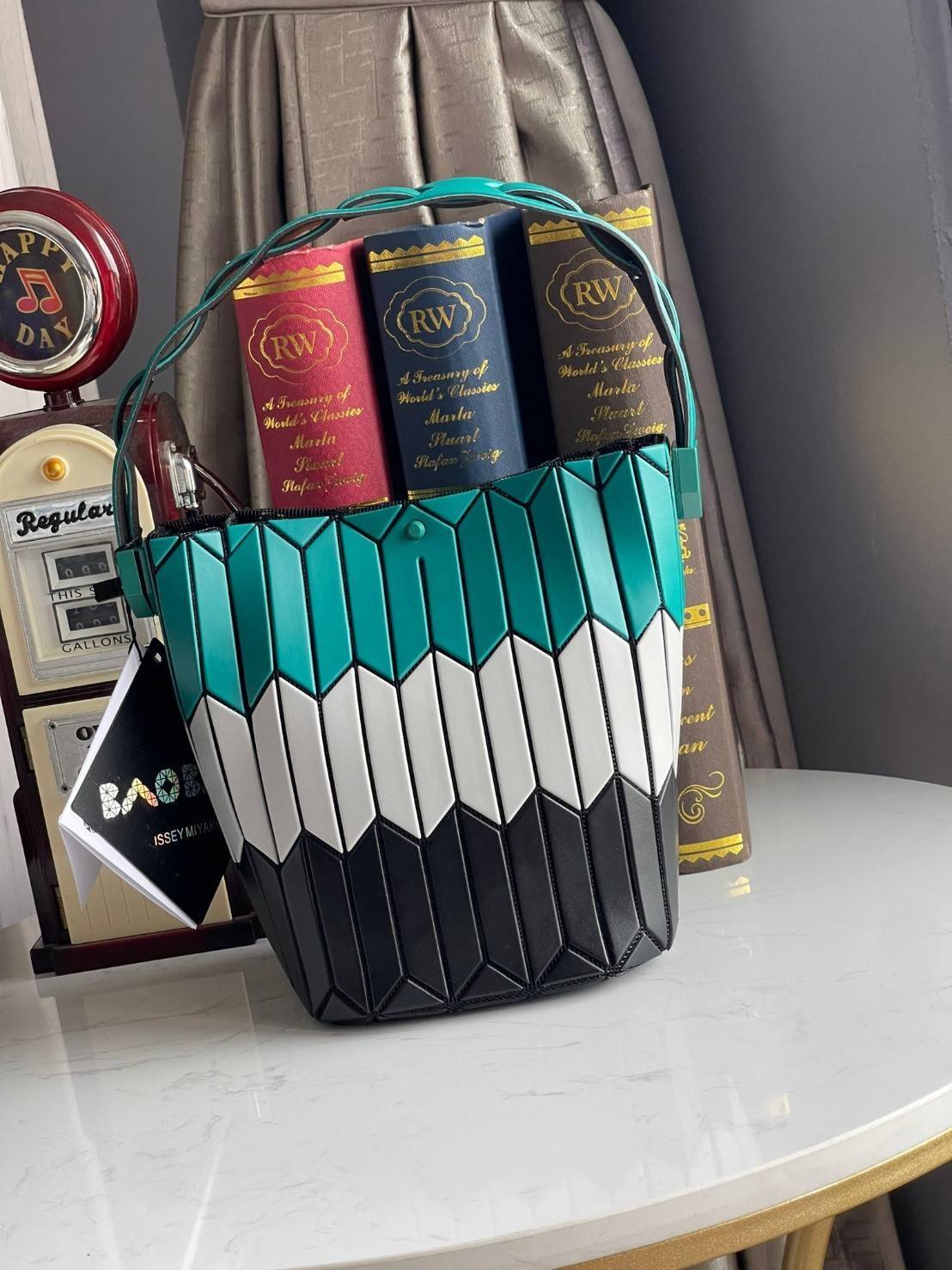 Small : BAO BAO ISSEY MIYAKE SMALL BUCKET เป็นกระเป๋าบัคเก็ตขนาดเล็กสามารถใช้ใส่กระเป๋าสตางค์และโทรศัพท์มือถือได้ ซีรีย์ใหม่นี้มีจุดเด่นที่แผ่นรูปทรงสี่เหลี่ยมด้านขนานในแนวตั้ง เกิดเป็นรูปทรงสามมิติซึ่งแตกต่างไปจากรูปทรงที่เกิดขึ้นจากแผ่นสามเหลี่ยม หูหิ้ว