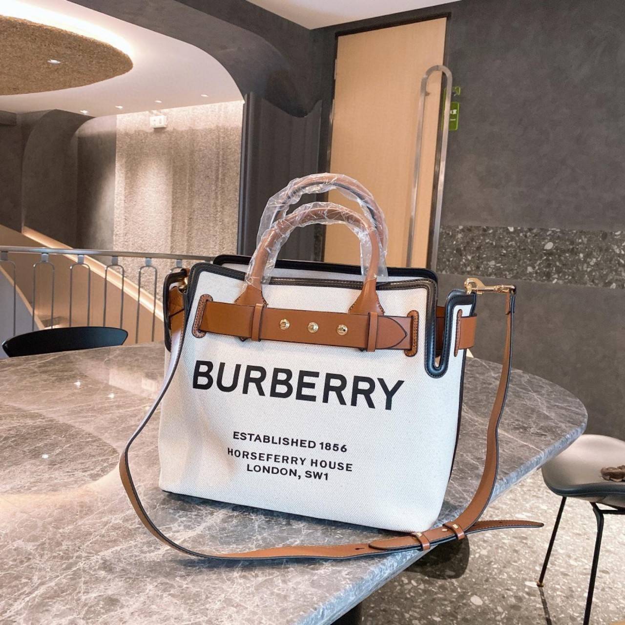 BURBERRY FRAGRANCES TOTE BAG อีกหนึ่งไอเท็มหายาก วัสดุ Canvas & Leather Calfskin ดีไซน์สวยมีเอกลักษณ์คาดด้วยสายหนังประดับกระดุมทองด้านหน้า หูจับหนังแท้จับถนัดมือ สายสะพายยาวหนังแท้ถอดได้ปรับระดับได้อะไหล่แบรนด์ ภายในโล่งกว้างมีช่องใส่ของใส่เอกสารA4 กระเป๋