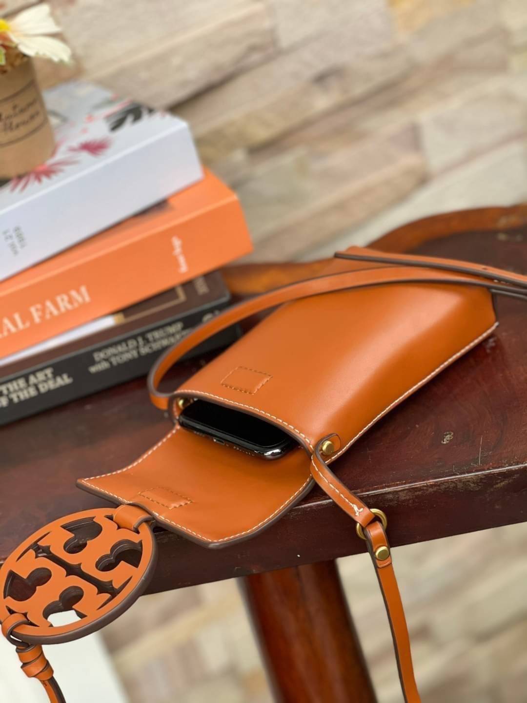 TORY BURCH MILLER METAL PHONE CROSSBODY อีกหนึ่งกระเป๋าใส่มือถือรุ่นฮิตที่เชื่อว่าหลาย ๆ คนต้องเคยเห็นผ่าน ๆ ตามาอย่างแน่นอน กับแบรนด์ Tory Burch ดีไซน์กระเป๋าทรงฝาพับแม่เหล็กใช้งานง่าย มาพร้อมดีเทล Logo แบรนด์โดดเด่นสีทองตัดกับหนังแกะสีดำ ดูหรูดูแพง! แต่