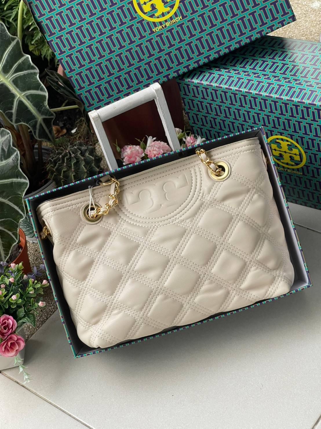 Tory Burch Fleming Soft Small Tote Bag เป็นกระเป๋าสะพายไหล่น่ารัก ๆ สักใบที่มีดีไซน์โดดเด่น สะดุดตา ใน Collection เรียกได้ว่าขายดีอันดับต้น ๆ ของแบรนด์ ใช้ได้ในลุคช์ทางการและกึ่งทางการ ดีเทลการตัดเย็บพิมพ์ลายนูนคู่กับแพทเทิร์นสี่เหลี่ยมทรงเพชร ที่ช่วยเพิ่