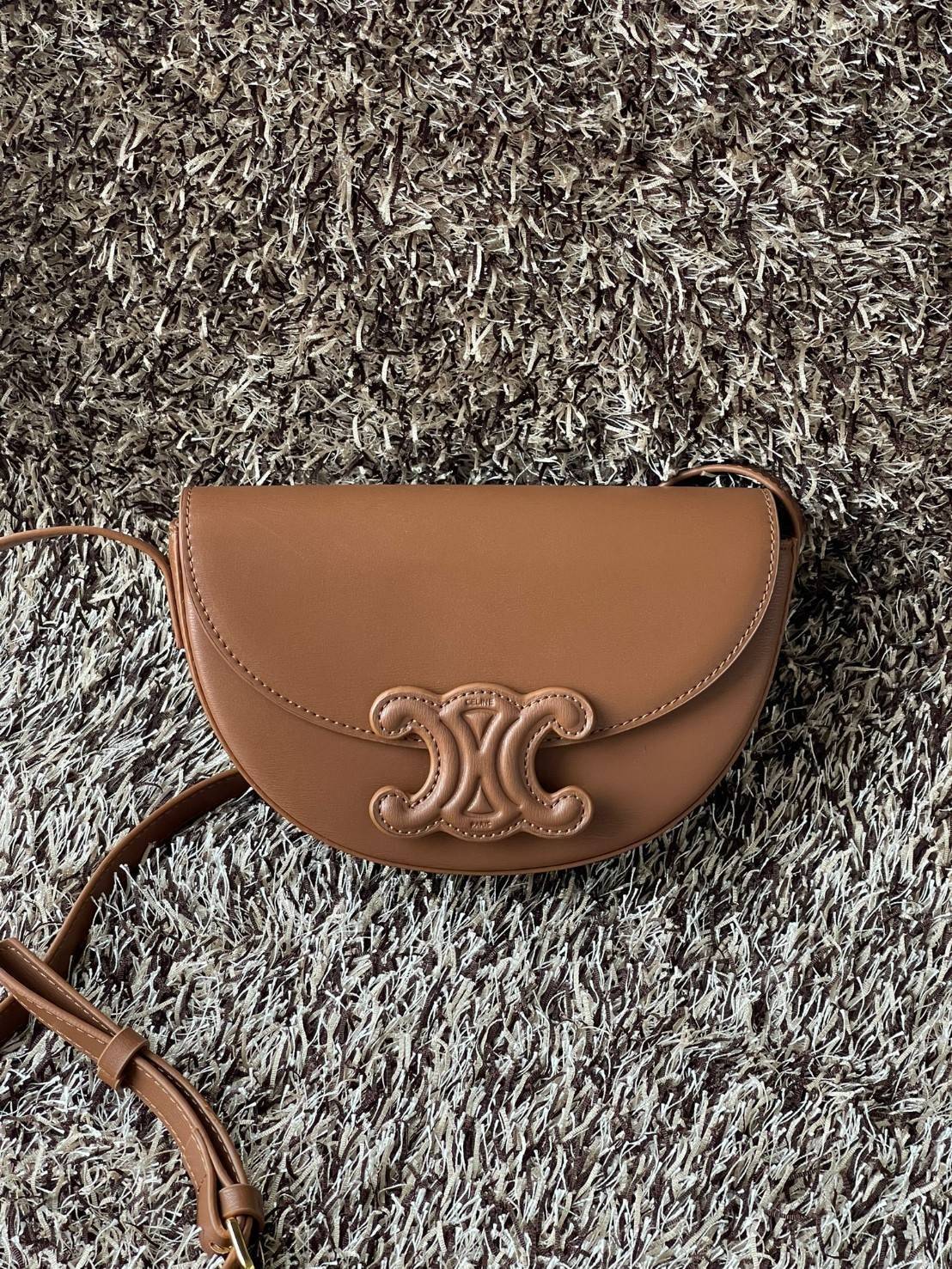 CELINE BESACE CUIR TRIOMPHE IN SMOOTH กระเป๋ารุ่นนี้นำเสนอในรูปทรงฮาล์ฟมูนที่ตอนนี้กำลังงมาแรง เปิดด้วยกระดุมแป๊กเพื่อเผยให้เห็นช่องภายในที่กว้างขวางและกระเป๋าด้านในแบบแบน คุณสมบัติที่โดดเด่นอีกอย่างของกระเป๋าอยู่ที่โลโก้ขนาดใหญ่ รูปทรงสะดุดตา สามารถสะพาย