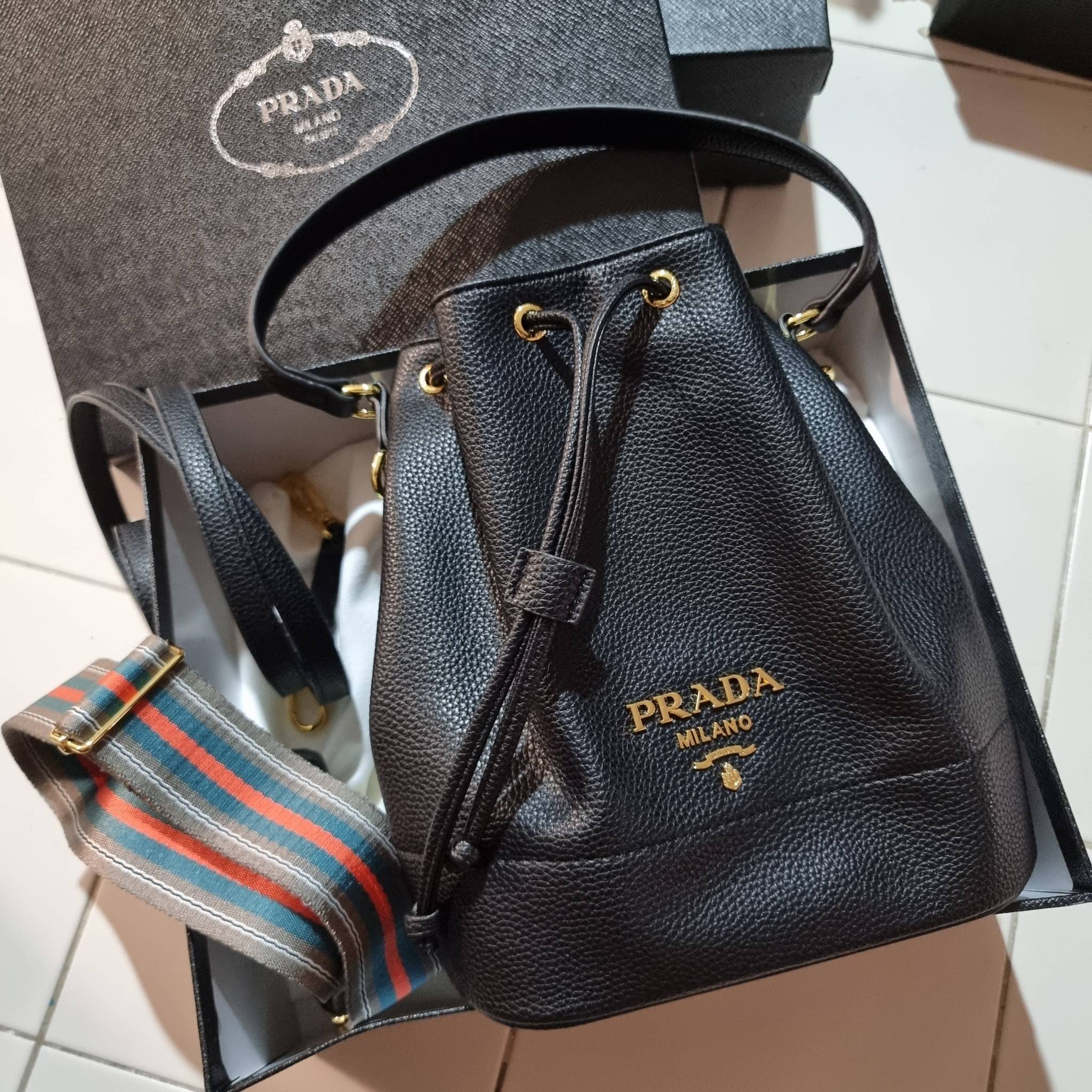 Prada leather bucket bag กระเป๋าสะพายทรงขนมจีบ ดีไซน์เรียบ แต่หรู น่าใช้มากๆ หนังสวยมาก วัสดุหนัง pepble สัมผัสนิ่มมือ ตกแต่งโลโก้สีทองตัดหนังดำ คือเลิศ!! ปากกระเป๋ารูดเปิดปิดได้ สะดวกใช้งาน ภายในโล่งกว้าง จุของได้เยอะ ไม่ธรรมดาเลย พิเศษ!! นอกจากสายคล้องใ