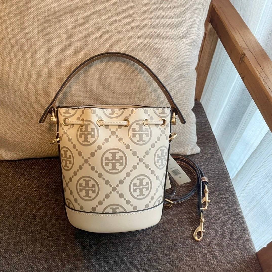 Tory Burch T Monogram Embossed Mini Bucket Bag กระเป๋าทรงถังขนาดเล็ก ประดับด้วยลวดลายอันเป็นสัญลักษณ์ของแบรนด์ ถูกประดิษขึ้นด้วยความพิถีพิถันวัสดุหนังอย่างดี ด้านในบุด้วยหนังไมโครซูแอคเนื้อนุ่มทำความสะอาดง่าย อะไหล่ทองหรูหรา มาพร้อมสายยาว ปรับสายได้ ถอดสา