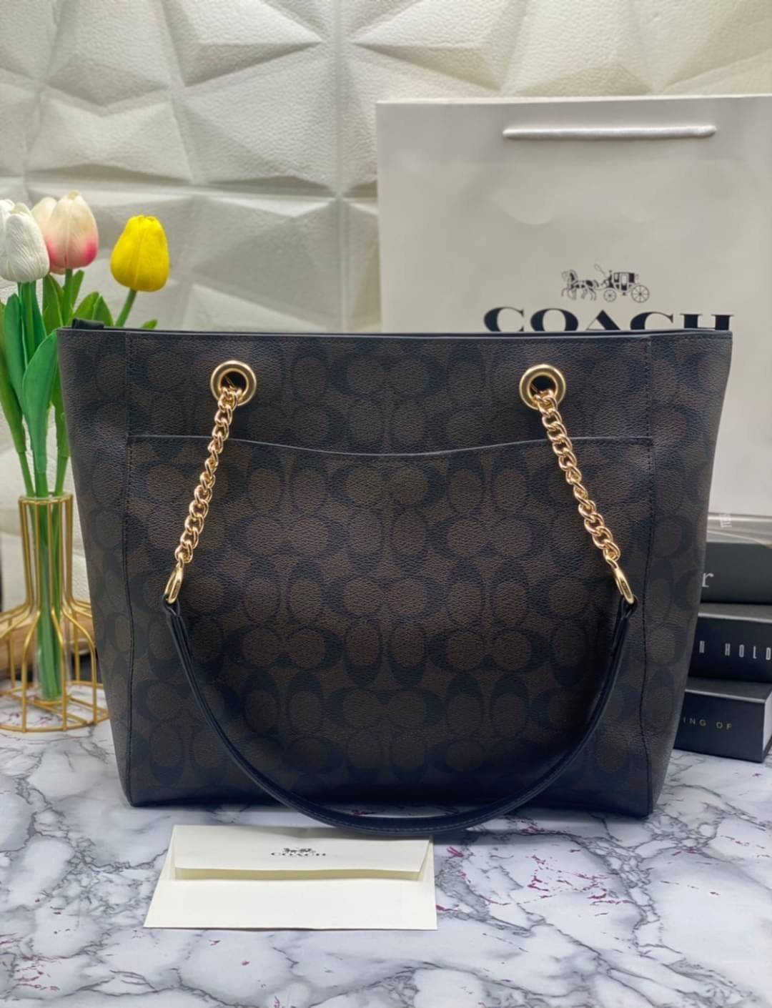 COACH Tote in Signature Canvas Bag กระเป๋าสะพายทรงช้อปปิ้ง สายกระเป๋าเป็นหนังสลับโซ่ทองสวยงาม เพิ่มความหรูหรา ภายในโล่งกว้างใส่ของได้เยอะมาก วัสดุ Canvas เคลือบลายซิกเนเจอร์และหนัง พร้อมซิปกลางเก็บของได้มิดชิดเลยค่ะ มี 3 สี น้ำตาล ดำ ขาว