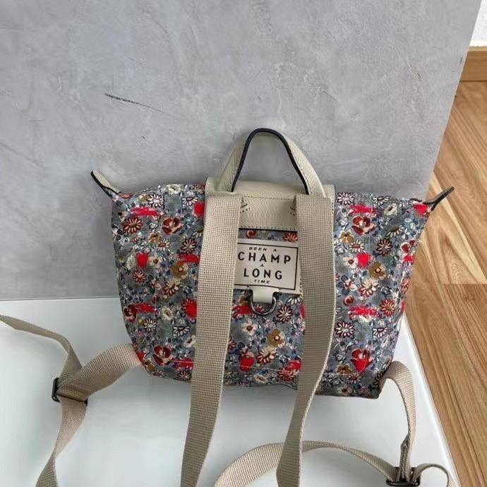 Longchamp X Eu Backpack กระเป๋าเป้สะพายหลังลายดอกๆไม้ วัสดุผ้าฝ้าย อะไหล่สีดำ กระเป๋าเป้แบบลำลองสำหรับสตรีซึ่งนำรูปทรงอันเป็นเอกลักษณ์ของ Le Pliage มาปรับใช้กับทุกสถานการณ์ อุปกรณ์เสริมที่ใช้งานได้จริงนี้มีสายรัดปรับระดับได้และที่จับช่วยให้ สะพายข้างหรือส