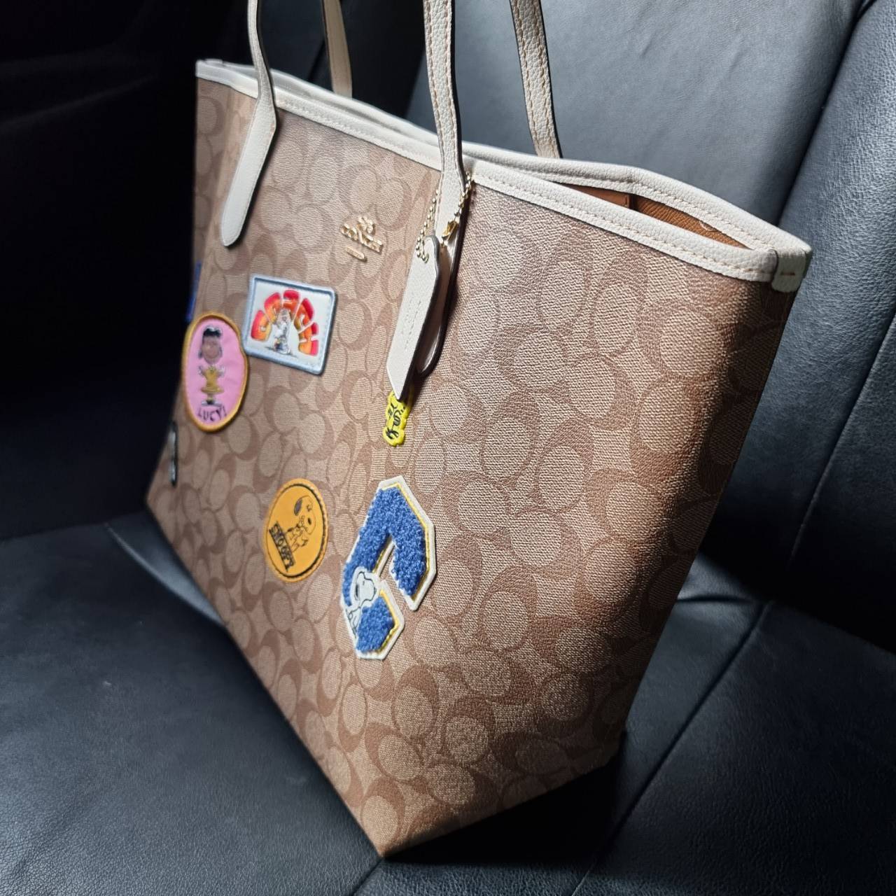 COACH C4292 COACHxPEANUTS CITY TOTE IN SIGNATURE CANVAS WITH VARSITY PATCHES กระเป๋าทรงโท้ทใบใหญ่ กับคอลเลคชั่นคอลแลบใหม่ล่าสุด น่ารักด้วยเหล่าผองเพื่อนสนู้ปพี สวยโดดเด่นมากๆ ใบนี้ใส่ของได้ของครบครัน จุได้แบบไม่ต้องกลัวเต็ม!! วัสดุหนังแคนวาสคุณภาพดี ปากกร