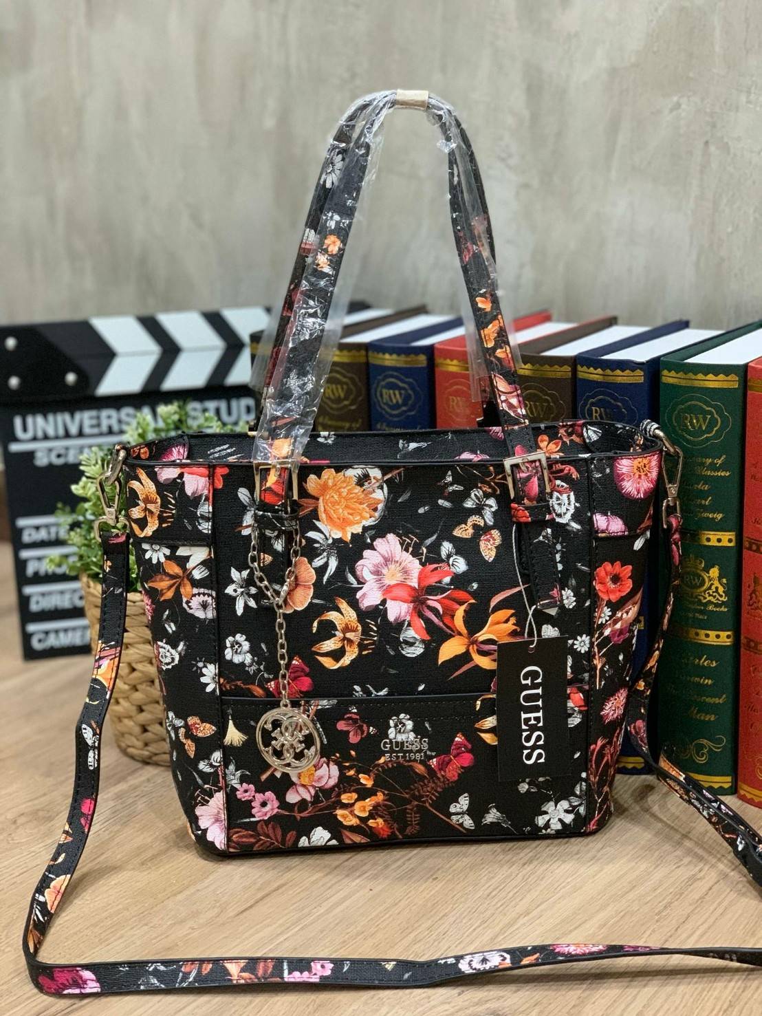 GUESS Women's Medium Floral Tote Bag กระเป๋าถือ คล้องไหล่หรือสะพาย ขนาดกลาง วัสดุหนังpu ลายดอกไม้ชนิดต่างๆรอบใบ เปิดปิดใช้งานด้วยซิปเดียวด้านบน ภายในมีกว้างใส่กระเป๋าสตาวค์ยาว มินิไอแพคได้ หูจับและสายสะพายปรับระดับได้ มาพร้อมกุญแจโลโก้guess สวยน่ารัก