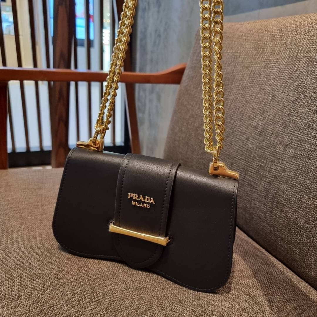 PRADA FRAGRANCE SHOULDER BAG WITH GWP ไอเท็มสุดโปรดที่ควรค่าแก่การครอบครองและเก็บสะสม กระเป๋าสะพายไหล่ สวยคม สีดำคลาสสิคตัดกับอะไหล่ทองเป็นอย่างดี วัสดุหนังแท้เต็มใบ เปิดปิดด้วยแถบหนังสอดในช่อง ใช้งานสะดวก พกพาง่าย ขนาดกำลังสวย สายสะพายในตัว สะพายได้หลากห