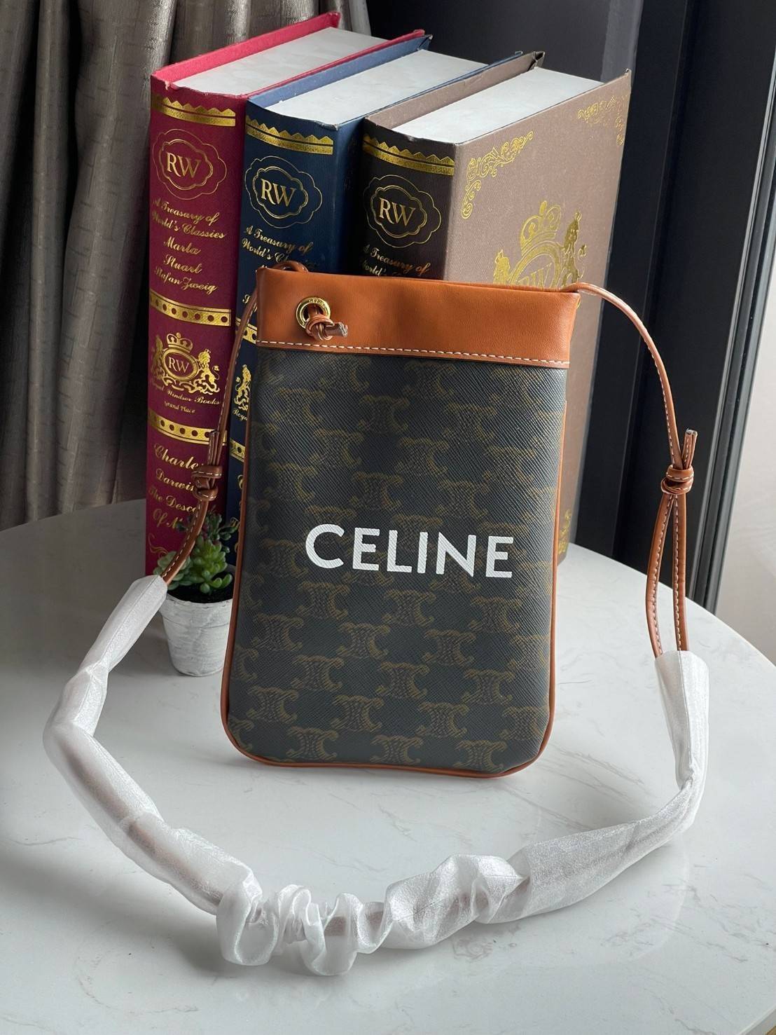 Celine Triomphe Pouch Crossbody Bag / Celine Phone Bag ในวันที่ต้องการความคล่องตัว เราสามารถหยิบกระเป๋าใส่โทรศัพท์ประเภทนี้เพื่อใส่เพียงแค่โทรศัพท์ เงิน และของสำคัญชิ้นเล็ก ๆ ได้เลย โดยไม่ต้องพกกระเป๋าใบใหญ่ ๆ ไปให้เกะกะ แถมยังดูเป็นแฟชั่นที่ทันสมัยอีกด้ว