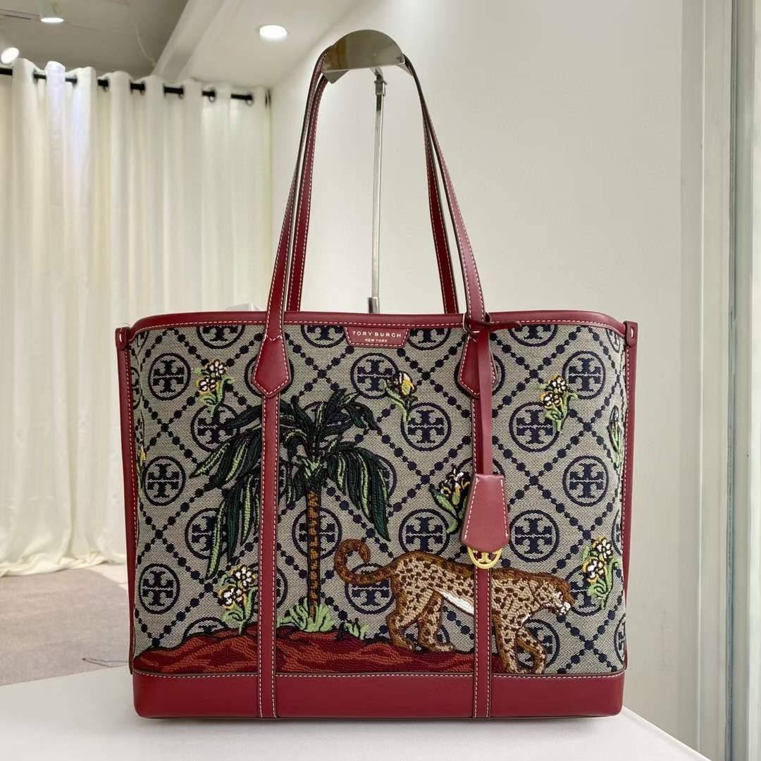 Tory Perry Embroidered T Monogram Triple Compartment Tote Bag เป็นแพทเทิร์นที่ได้รับแรงบันดาลใจจากการควิลท์สไตล์เพนซิลเวเนียดัตซ์ดั้งเดิมและเฉลิมฉลองโลโก้อันเป็นสัญลักษณ์ของแบรนด์ วัสดุผ้าแจ็คการ์ดแบบทอหนัง อะไหล่ทอง โดดเด่นด้วยลายเสือชีร์ต้าร์ งานเย็บปัก