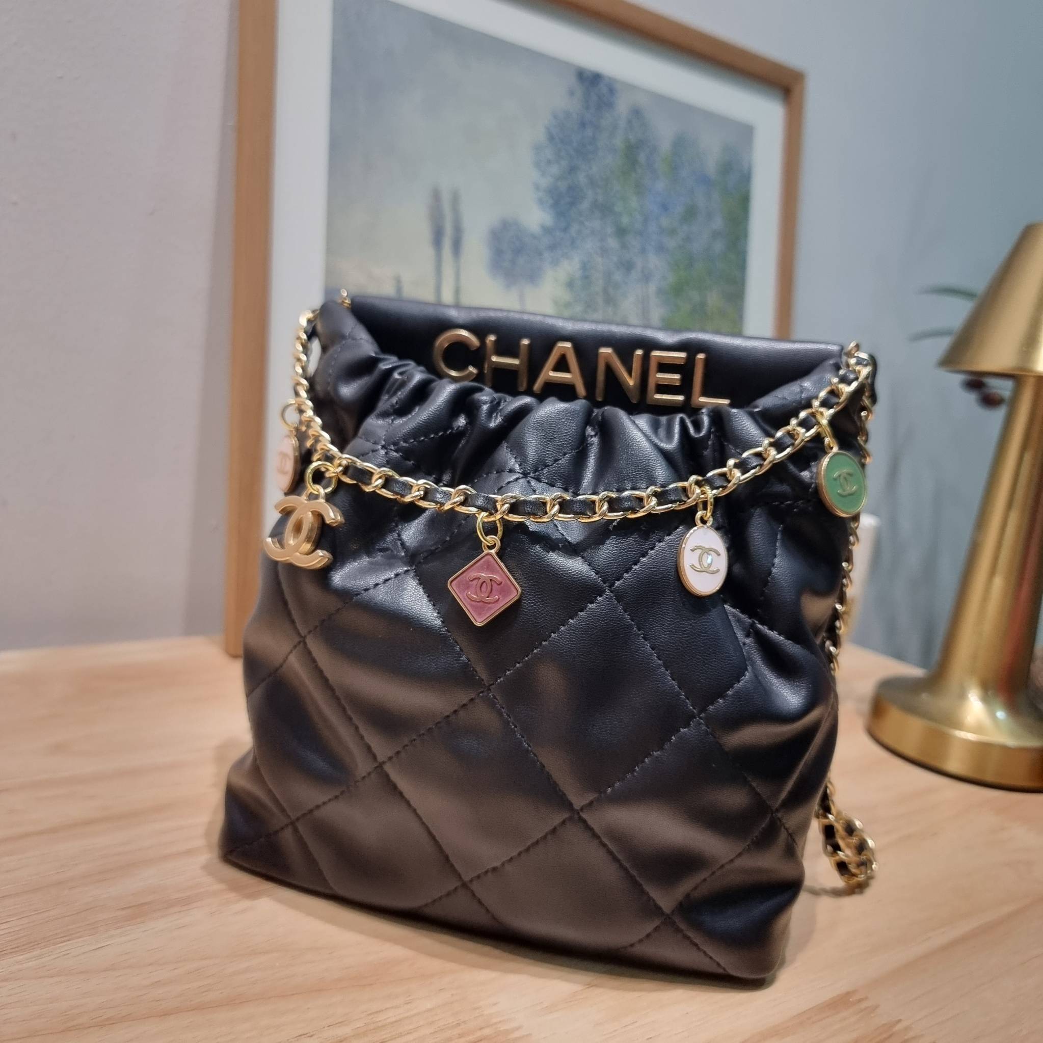 Chanel 23P mini bucket bag น่ารักมากๆ กับกระเป๋าสะพายไซส์มินิ ที่ปล่อยผ่านไม่ได้จริง ดีไซน์สายโซ่คล้องแขนตกแต่งอะไหล่ห้อยเพิ่มมูลค่า และยังตกแต่งโลโก้สวยเด่น