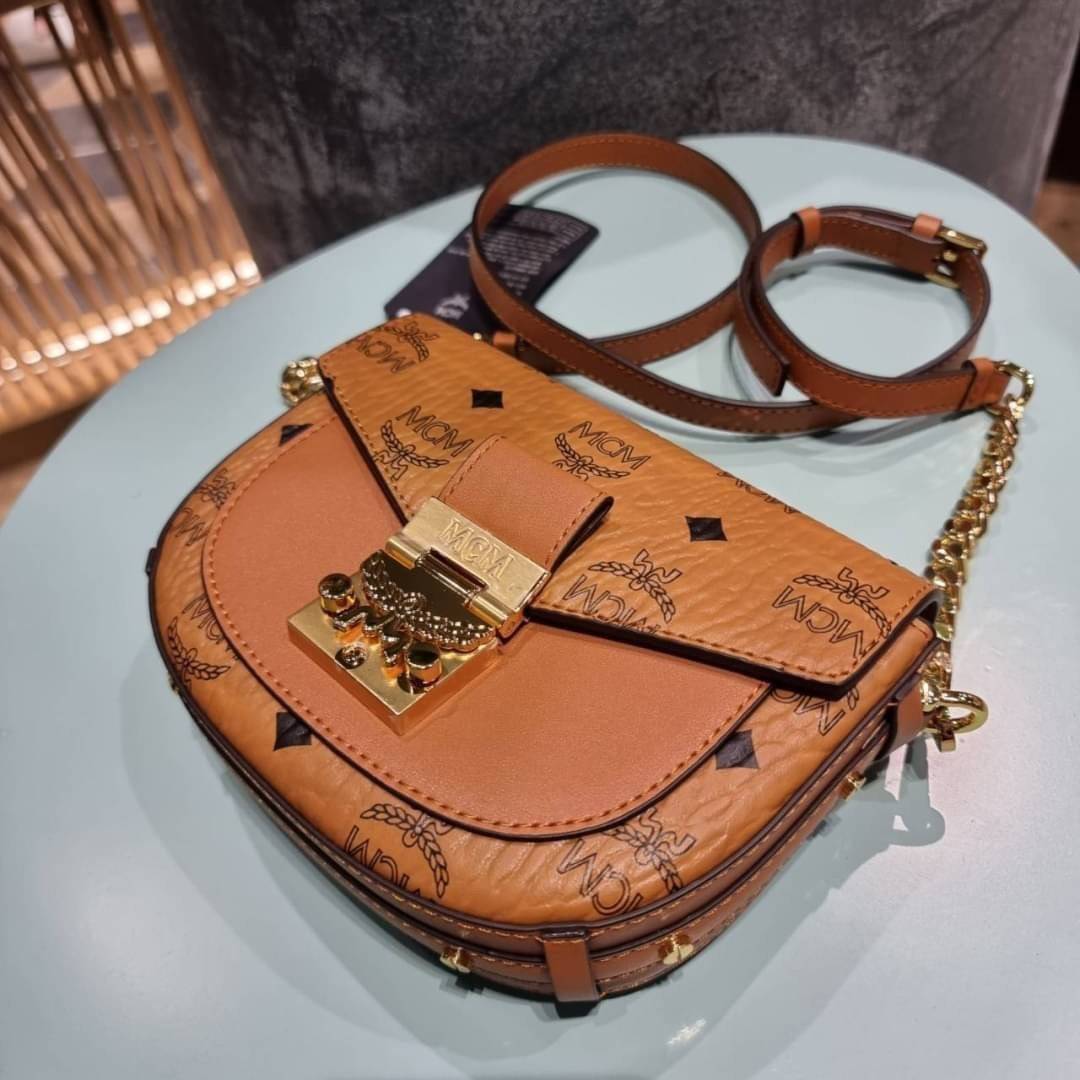 M.C.M MINI PATRICIA CROSSBODY IN VISETOS กระเป๋าสะพายไซส์มินิ แรงดีไม่มีตกน้า คอลเลคชั่นนี้ดีไซน์แปลกใหม่ ทรงโค้งมน สวยหรู ด้านข้างตกแต่งหมุดทองรอบใบ วัสดุตัวกระเป๋าเป็นหนังแคนวาสคุณภาพดี ภายในเป็นหนังกลับสีส้มโดดเด่นเป็นเอกลักษณ์ มีช่องใส่บัตรแยกให้ เปิด