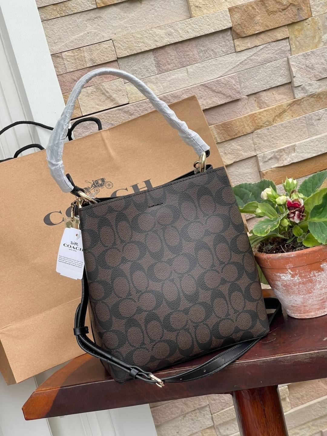 COACH SMALL TOWN BUCKET BAG IN SIGNATURE สำหรับสาวแฟชั่นที่ชอบรายละเอียดชิคๆ ดีไซน์สุดเก๋ แนะนำเลยสำหรับกระเป๋าทรงบักเก็ตใบนี้ เชื่อว่าสาว ๆ หลายคนชื่นชอบ เป็นไอเทมที่สามารถแมทช์ได้กับเสื้อหลากหลายสไตล์ บรรจุของได้เยอะโดยที่กระเป๋าไม่เสียทรง แบ่งช่องใช้งา