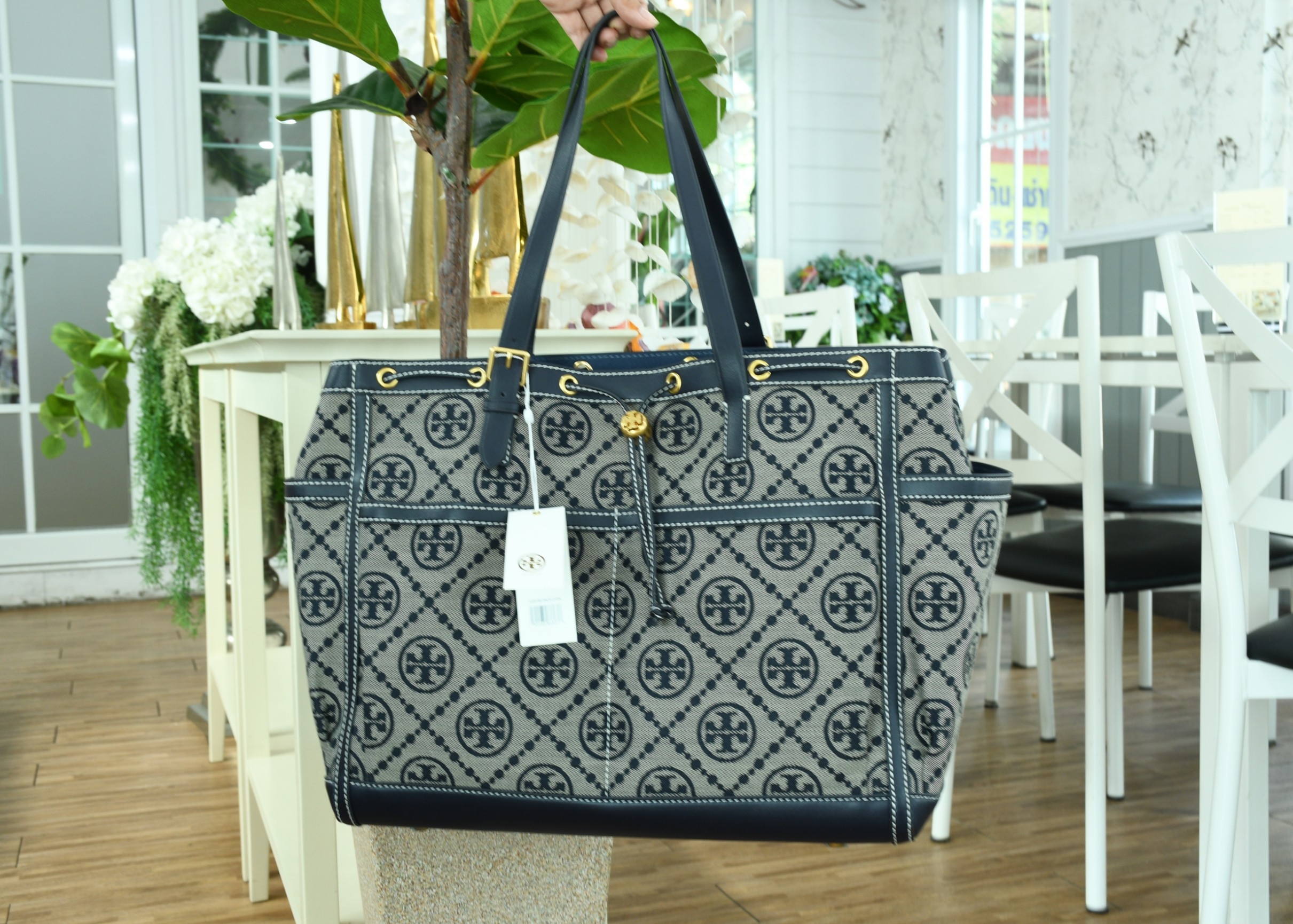 OUTLET 】TORY T MONOGRAM JACQUARD WFH TOTE กระเป๋าถือหรือสะพายไหล่ วัสดุ Canvas ปักษ์ลายแบรนด์ อะไหล่ทองสวยหรู น้ำหนักเบา จุของได้เยอะ ด้านหน้ามีกระเป๋าเล็ก2ช่อง ด้านหลัง2ช่อง ด้านในโล่ง มีช่องใหญ่1ช่อง ช่องเล็ก1ช่อง และอีก1ช่องซิป ใบใหญ่ Size XL ใส่เสื้อผ