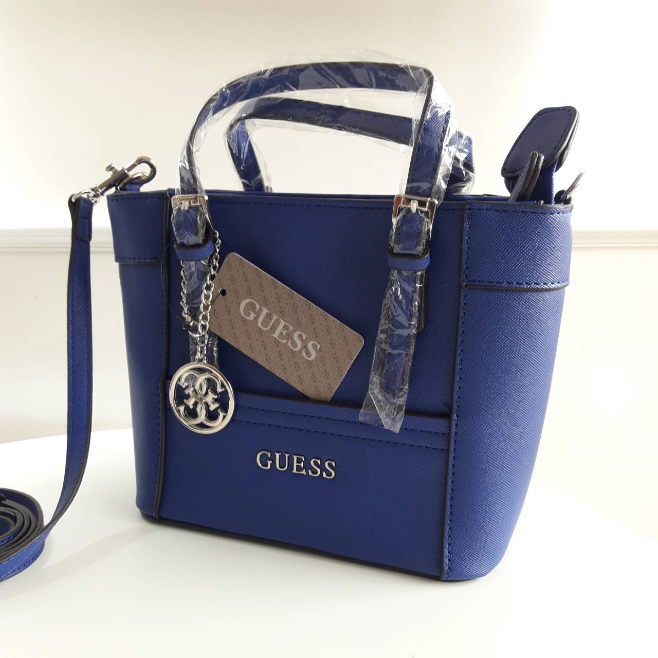 New! guess mini tote saffiano bag ลายหนัง Saffiano สวยอยู่ทรงสไตล์ PRADA ขนาดกำลังดีน้ำหนักเบา ด้านหน้าประดับโลโก้แบร์น พร้อมพวงกุญแจโลโก้แบรนด์ห้อยที่หูกระเป๋าสามารถถอดเเยกใช้ได้ เปิดปิดด้วยซิปสะดวกใช้ ภายในมีโลโก้ ช่องซิปและช่องเล็กใส่มือถือ ซับในพิมโลโ