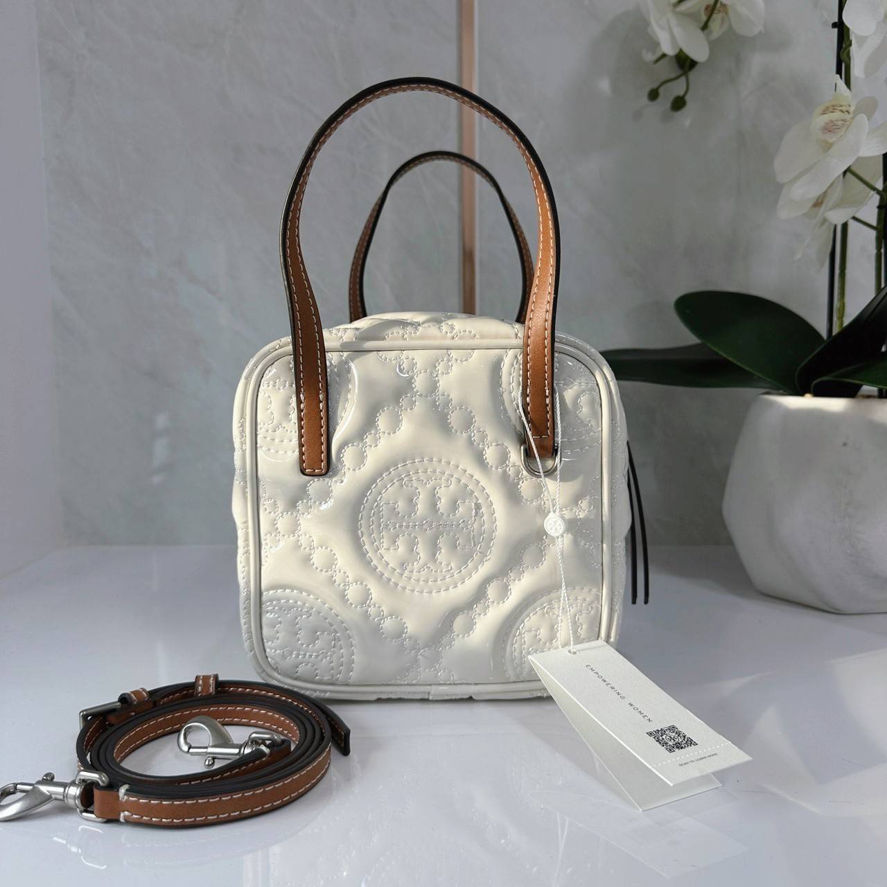 Tory Burch T Monogram Embroidered Patent Cube คอลเลคชั่นใหม่ รุ่นลิมิเต็ดรูปทรงใหม่ T Monogram สุดcube วัสดุหนังแท้ เปิด-ปิดด้วยซิป ภายในกว้าง มีช่องแยก 1 ช่อง สามารถใส่โทรศัพท์มือถือได้ทุกรุ่น สามารถถือหิ้วหรือสะพายได้ สายสามารถถอดและปรับระดับได้คะ
