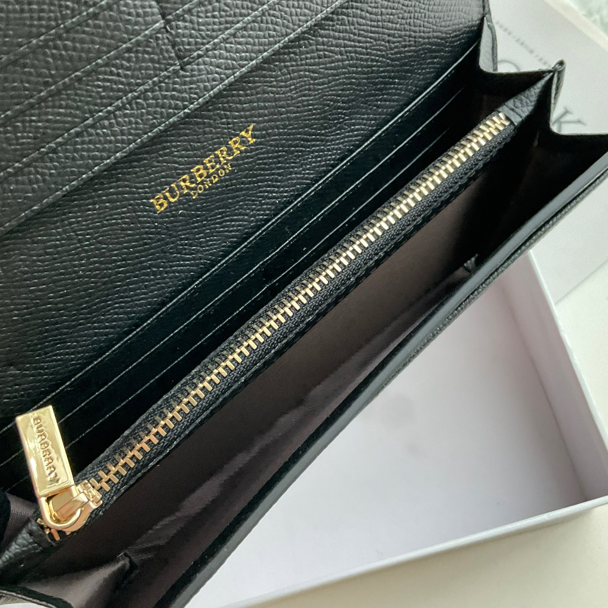 กระเป๋าสตางค์รับทรัพย์ ทรงหรู จากงาพรีเมี่ยมกิ๊ฟ Limited Edition จาก BURBERRY กระเป๋าสตางค์ใบยาวแบบพับกระดุม ทูโทนด้วยหนังแท้คาดผ้าลาย vintage ด้านในมีช่องใส่ธนบัตรยาวทั้งสองฝั่ง ช่องใส่บัตรได้อย่างน้อย 12 ช่อง และช่องเปิดด้วยซิปปั้มแบรนด์อะไหล่ทองสุดหรู 