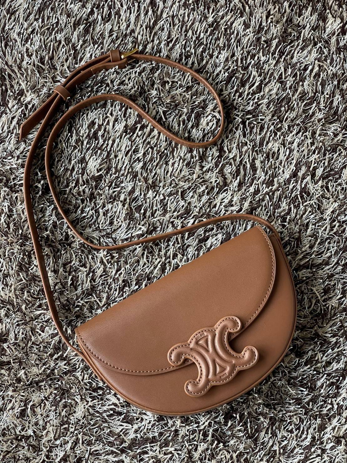 CELINE BESACE CUIR TRIOMPHE IN SMOOTH กระเป๋ารุ่นนี้นำเสนอในรูปทรงฮาล์ฟมูนที่ตอนนี้กำลังงมาแรง เปิดด้วยกระดุมแป๊กเพื่อเผยให้เห็นช่องภายในที่กว้างขวางและกระเป๋าด้านในแบบแบน คุณสมบัติที่โดดเด่นอีกอย่างของกระเป๋าอยู่ที่โลโก้ขนาดใหญ่ รูปทรงสะดุดตา สามารถสะพาย