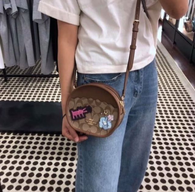 COACH KEITH HARING CANTEEN CROSSBODY IN SIGNATURE CANVAS WITH PATCHES F48730 กระเป๋าทรงกลมสุดเก๋ ไม่เหมือนใคร ตกแต่งลายให้มรความน่ารัก โดดเด่นขึ้นมา สะพายไปไหนก็สวยไม่เหมือนใคร ภายในกว้าง ใส่ของได้เยอะ กระเป๋าเปิดปิดด้วยซิป ใครย้งไม่มี รีบจับ รีบจองกันเลย