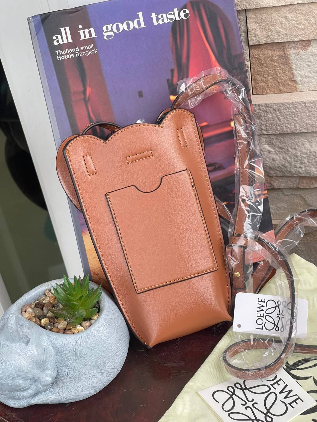 Loewe Leather Elephant Phone Holder แบรนด์หรูจากประเทศสเปนอย่าง โลเอเว่ (LOEWE) หลายๆคนคงนึกถึงกระเป๋ารูปทรงช้างขนาดเล็ก ที่เป็นเหมือนหนึ่งในซิกเนเจอร์ของแบรนด์ มีทั้งแบบสะพายข้าง แบบถือ รวมไปถึงในแบบเครื่องหนังชิ้นเล็กอย่างกระเป๋าใส่มือถือรุ่นนี้ ผลิตจาก