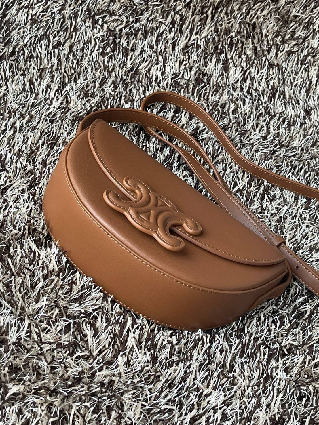 CELINE BESACE CUIR TRIOMPHE IN SMOOTH กระเป๋ารุ่นนี้นำเสนอในรูปทรงฮาล์ฟมูนที่ตอนนี้กำลังงมาแรง เปิดด้วยกระดุมแป๊กเพื่อเผยให้เห็นช่องภายในที่กว้างขวางและกระเป๋าด้านในแบบแบน คุณสมบัติที่โดดเด่นอีกอย่างของกระเป๋าอยู่ที่โลโก้ขนาดใหญ่ รูปทรงสะดุดตา สามารถสะพาย