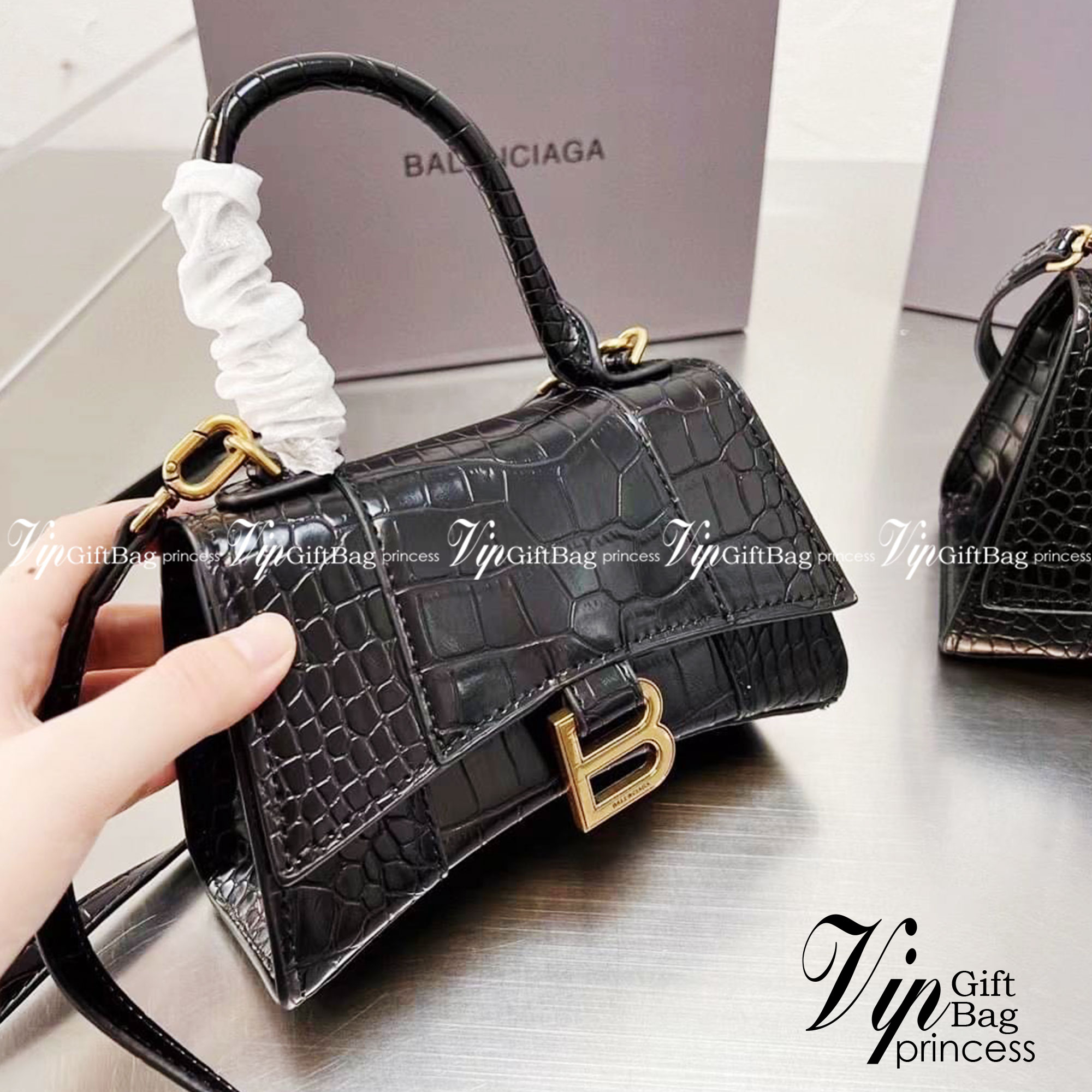 BALENCIAGA Hourglass BAG XS S / BALENCIAGA Hourglass Crocodile embossed calfskin กระเป๋าสะพายแบรนด์หรูซิกเนเจอร์ใบล่าสุด ที่มาพร้อมดีไซน์โดดเด่น มีความโฉบเฉี่ยว โค้งมนเหมือนพระจันทร์เสี้ยว เพิ่มความโดดเด่นสะดุดตาด้วยการตกแต่งอักษร B เมทัลลิก ที่เป็นเอกลัก