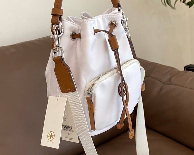 Tory Burch Virginia Nylon Bucket Bag / Tory Burch logo-plaque bucket bag กระเป๋าสะพายทรงบัคเก็ต เปิด-ปิดหนังรูดปากกระเป๋า มีหูหิ้วในตัว คล้องแขนเก๋ๆ ภายในเป็นช่องโล่ง มีช่องย่อย ใส่ของสำคัญจุกจิกได้ มีสายครอส จะสะพายไปไหนก็ได้ทุกโอกาส สวยเลิศทุกสี พร้อมส่