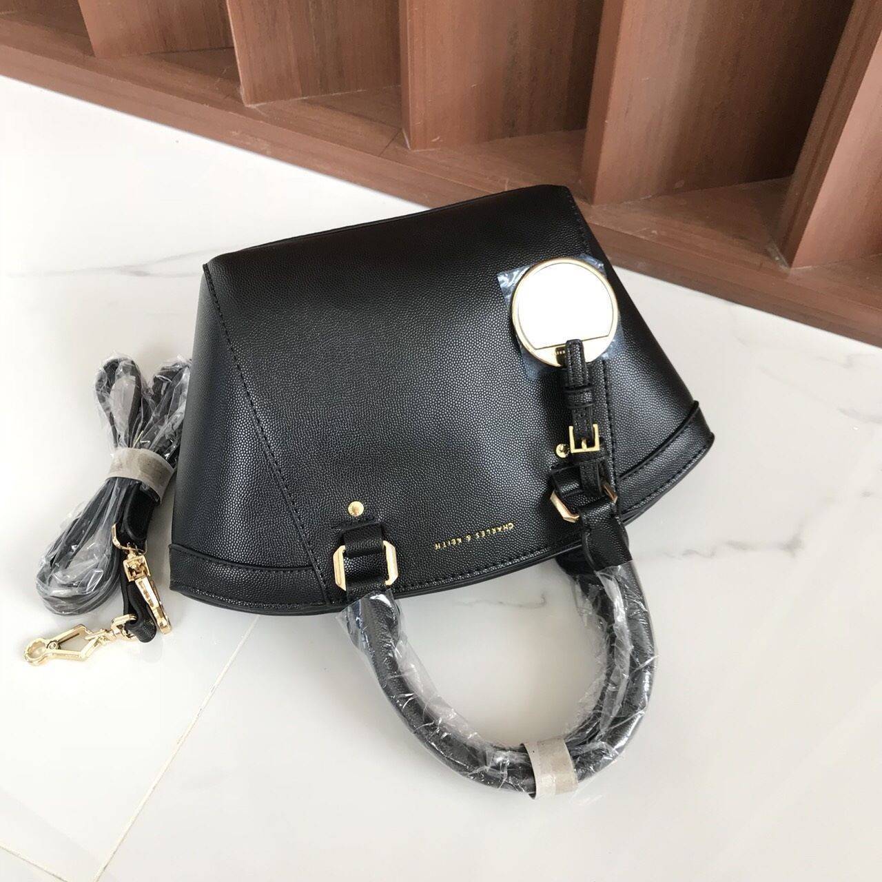 CHARLES & KEITH CITY BAG กระเป๋าถือหรือสะพาย ตั้งอยู่ทรงสวย มีโลหะรองฐาน เปิดปิดด้วยซิปเดียว ภายในมี 2 ช่องเล็กด้านหน้าประดับด้วยกระจกทรงกลม ใช้งานได้จริง ปั้มโลโก้แบรนด์ มาพร้อมสายสะพายยาว ปรับระดับและถอดสายได้ หูพับลงได้ น้ำหนักเบา ต้องมีไว้ครอบครองสักใ