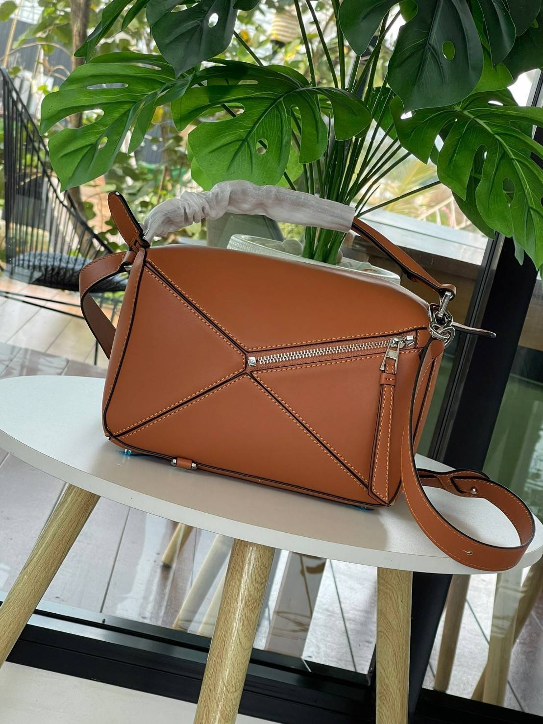 Loewe Puzzle Bag In Classic กระเป๋าทรง Puzzle นี้ออกแบบโดย Jonathan Anderson โดยได้รับแรงบันดาลใจในการออกแบบมาจากรูปทรงของลูกรักบี้ ดังนั้น จึงจะเห็นได้ว่าการตัดเย็บและรูปทรงของกระเป๋านั้นคล้ายคลึงกับลูกรักบี้ รูปทรงดูมินิมอลไม่ทิ้งคอนเซ็ปต์ของแบรนด์ สามา