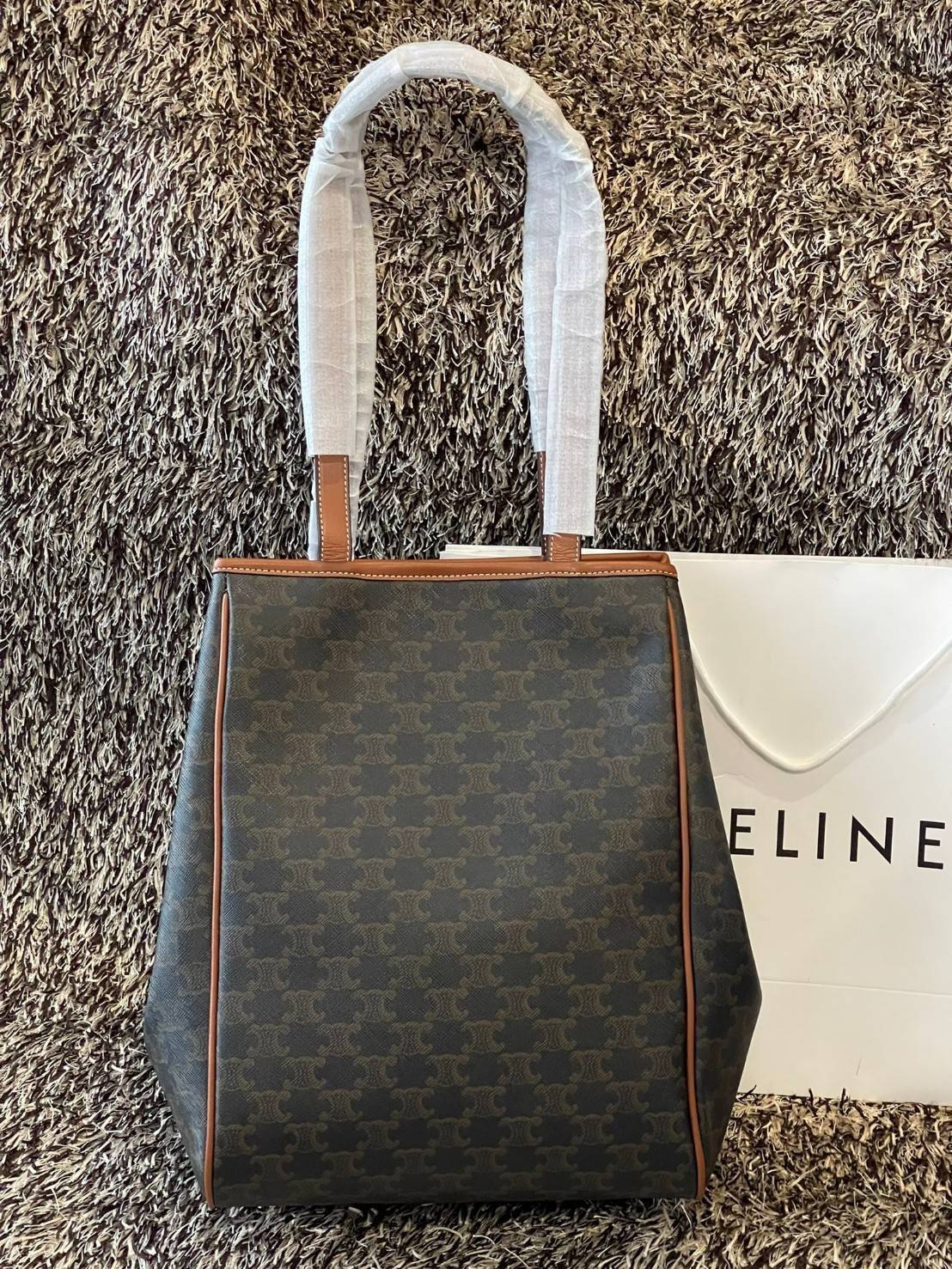 Celine Medium shopping bag in Triomphe canvas มาในรูปแบบ กระเป๋า Shopping Bag ใบสวยสง่า เป็นกระเป๋าดีไซน์เรียบง่าย แมตช์ได้กับทุกชุด ผลิตจากผ้าแคนวาสชนิดพิเศษซึ่งโดดเด่นด้วยลายเอกลักษณ์ของ Triompe เป็นใบที่เหมาะกับการใช้ประจำวันเป็นอย่างมาก ด้วยรูปทรงสี่เ