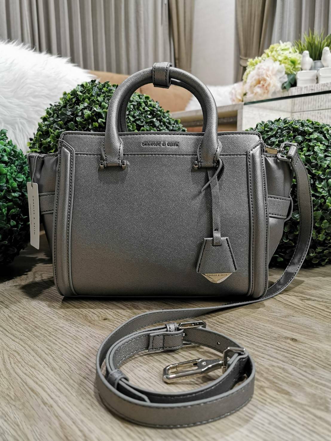 CHARLES & KEITH SAFFIANO TRAPEZE BAG กระเป๋าถือหรือสะพายรุ่นยอดนิยมดีไซน์สวยหรูวัสดุหนังคาเวียร์อยู่ทรง ด้านข้างเเต่งหนังช่องตัดดูมีดีเทล ด้านหน้ามีโลโก้ ด้านหลังมีช่องซิป เปิดปิดด้วยซิปหัวซิปแบรนด์ หูจับเเข็งแรง พับลงได้ พร้อมสายสะพายหนังปรับระดับได้ถอดไ