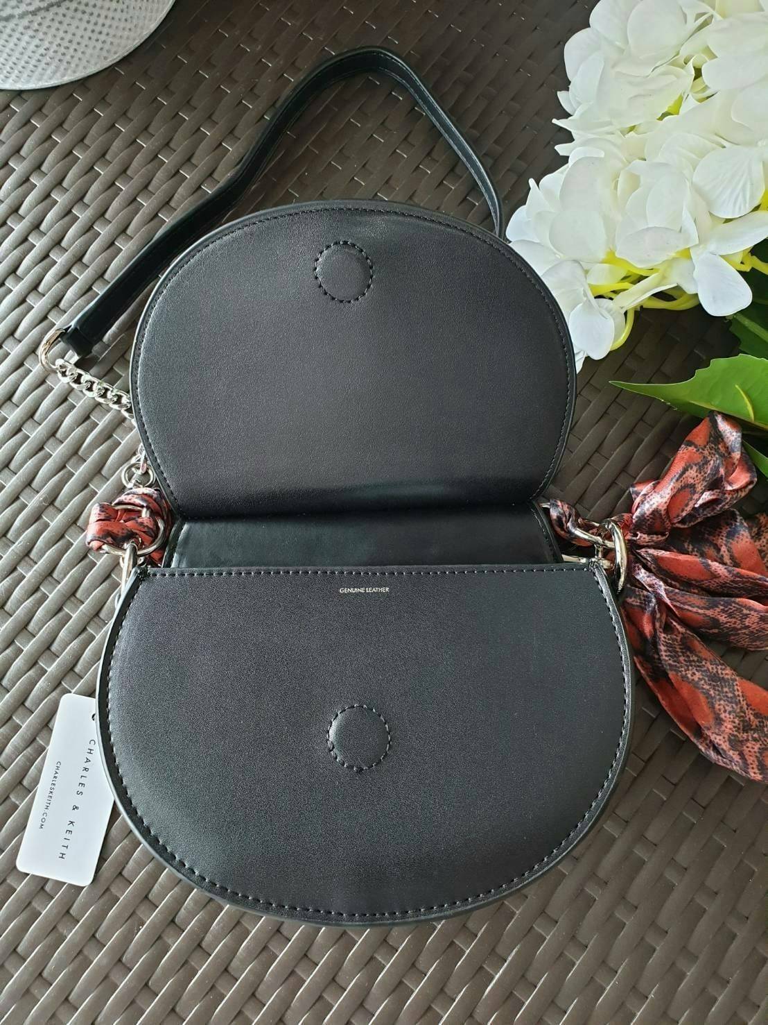 CHARLES & KEITH รุ่น LEATHER SATIN SCARF CROSSBODY BAG SL2-50150828 ราคาปกติช้อป ( ฿3,590.00 ) กระเป๋าถือ และ สะพาย ทรงโค้งมน หนังเรียบ ตั้งอยู่ทรง ด้านหน้าติดโลโก้แบรนด์ อะไหล่เงิน หูจับสายกระเป๋าร้อยเข้ากับห่วงเหล็กกลมๆ ด้วยผ้าลายสวยงามผูกเป็นโบว์เก๋ๆ ถ