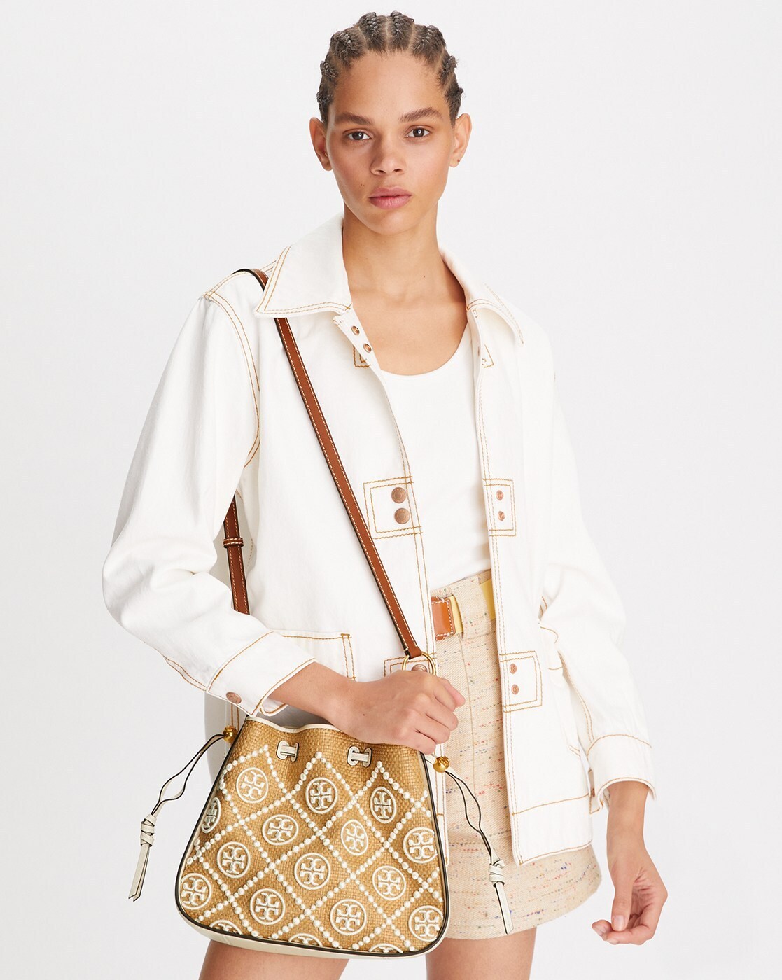 TORY BURCH T Monogram Straw Bell Bag กระเป๋าสะพายข้างรุ่นคลาสสิกที่ได้แรงบันดาลใจจากการควิลท์แบบดั้งเดิมของเพนซิลเวเนีย คอลเลกชันบ่งบอกถึงความมีสไตล์เหนือกาลเวลา รูปทรงเรียวโดดเด่น ปักทอลายแบรนด์อย่างสวยงาม เปิด ปิดด้วยเชือกรูด ด้านในช่องโล่งกว้าง ซับในผ้