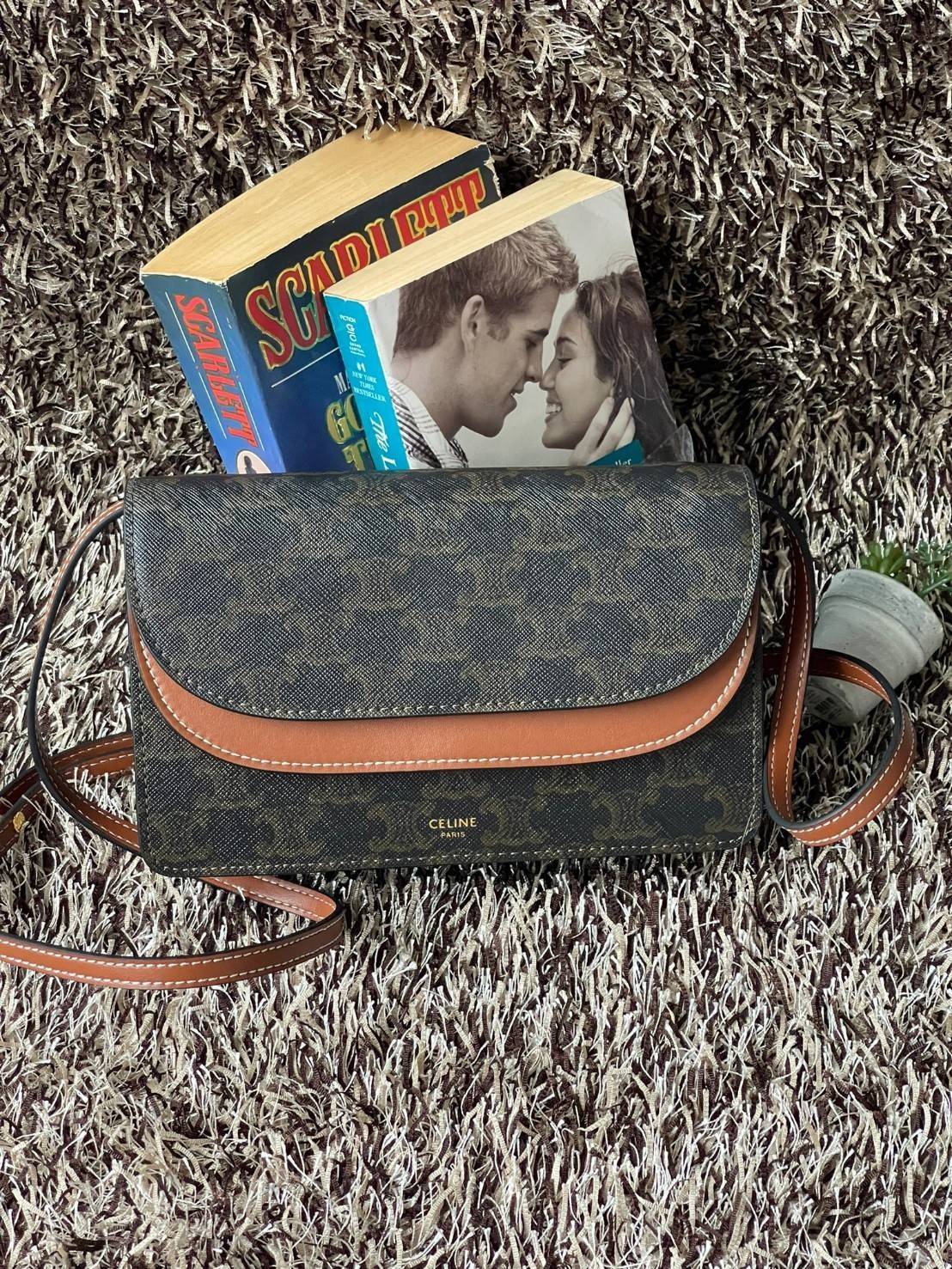 CELINE WALLET ON STRAP IN TRIOMPHE CANVAS กระเป๋าสะพายไหล่สุดเก๋ใบนี้ผลิตจากผ้าใบเคลือบอย่างดีพร้อมขอบหนังสีน้ำตาล กระเป๋ามีสายสะพายหนังสีน้ำตาลพร้อมฮาร์ดแวร์สีทอง ถอดสายออกเพื่อเป็นกระเป๋าถือทรงคลัชท์เปลี่ยนลุคช์ ลวดลายtriomphe ความเป็นแบรนด์ CELINE ได้อ