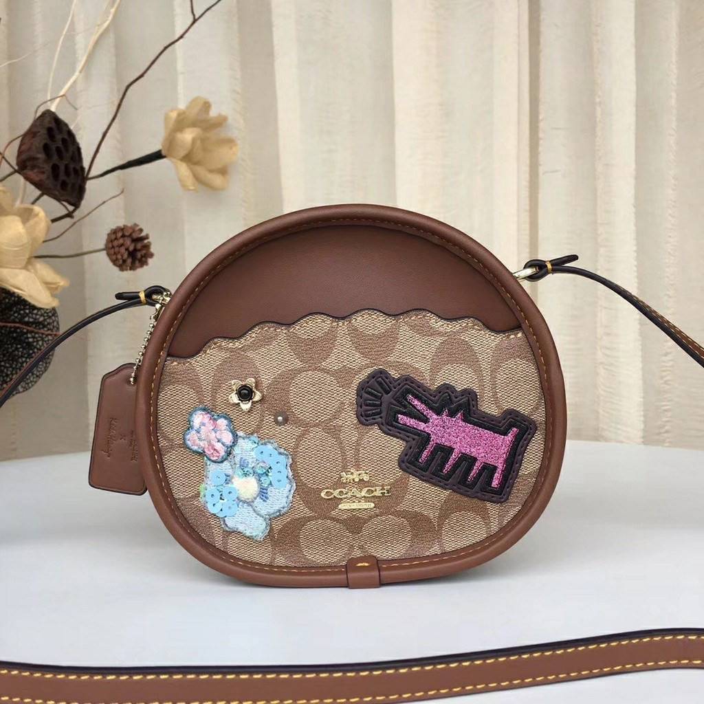 COACH KEITH HARING CANTEEN CROSSBODY IN SIGNATURE CANVAS WITH PATCHES F48730 กระเป๋าทรงกลมสุดเก๋ ไม่เหมือนใคร ตกแต่งลายให้มรความน่ารัก โดดเด่นขึ้นมา สะพายไปไหนก็สวยไม่เหมือนใคร ภายในกว้าง ใส่ของได้เยอะ กระเป๋าเปิดปิดด้วยซิป ใครย้งไม่มี รีบจับ รีบจองกันเลย