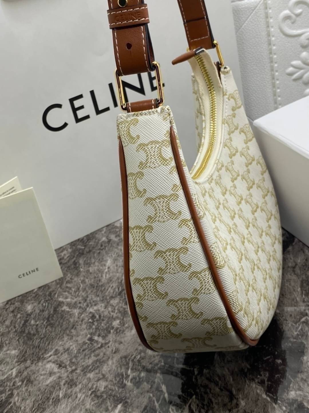 หนังแท้ CELINE AVA / CELINE Vintage Classic Ava bag 1 ใน คอลเลคชั่น “Triomphe Canvas” มาพร้อมสายสะพายไหล่ที่ปรับความยาวได้ และเนื่องจากช่วงล่างของกระเป๋ามีขนาดใหญ่กว่าช่วงบน จึงทำให้ไม่เสียทรงเมื่อเราใส่สิ่งของอย่างกระเป๋าสตางค์หรือโทรศัพท์มือถือ หากดูภาพ