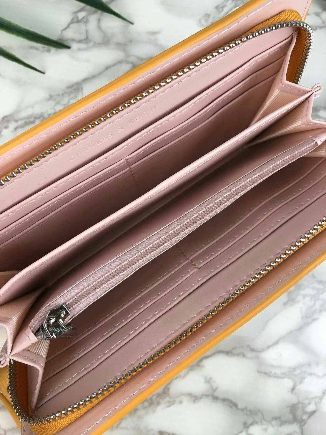 CHARLES & KEITH CLASSIC ZIP AROUND WALLET กระเป๋าเงินใบยาวซิปรอบ มีสายคล้องมีสีเข้ากระเป๋า 1 เส้น ใช้งานง่ายมากๆ คล้องมือก็เก๋ ด้านหน้าปั๊มโลโก้แบรนด์ เปิดปิดด้วยซิปรอบ ที่สายคล้องมือแต่งหมุดสีสวยเด่น ถอดสายได้ จุบัตรได้ 12 ใบ มีช่องซิปใส่เหรียญและช่องใส่