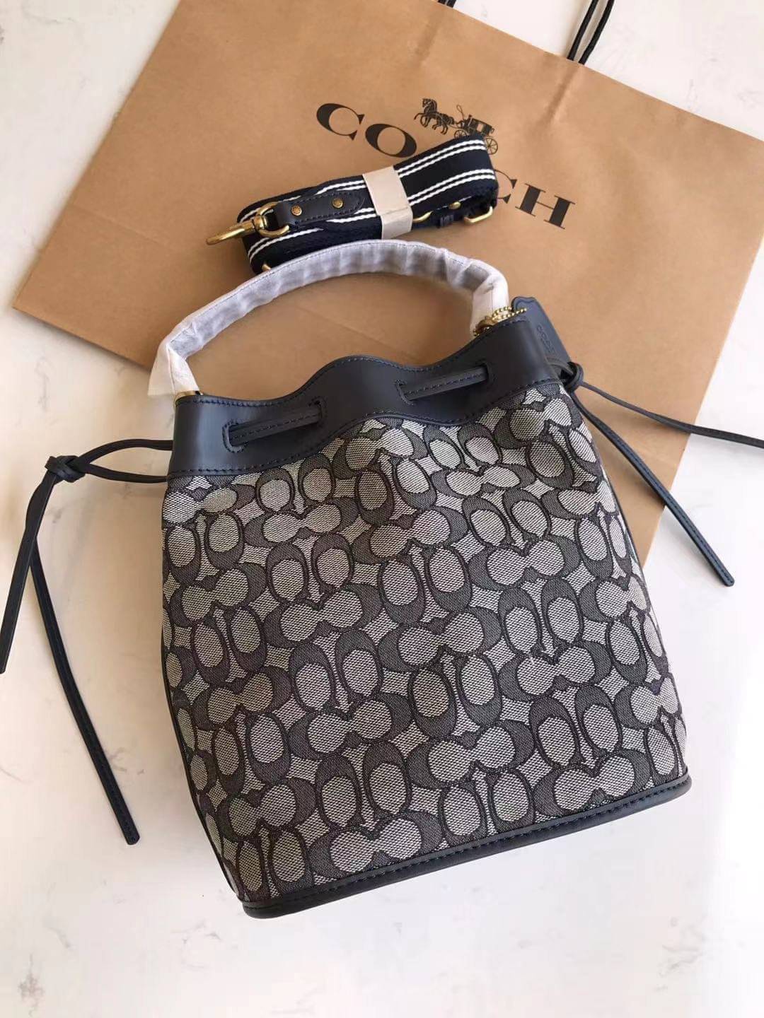 COACH FIELD BUCKET BAG IN SIGNATURE JACQUARD C3853 กระเป๋าสะพายทรงบัคเก็ต รุ่นใหม่ล่าสุด ดีไซน์ลายซิกเนเจอร์บนผ้า jacquard สวยคม เป็นเอกลักษณ์ไม่ซ้ำใคร มาพร้อมสายสะพายผ้าสปอร์ต และสายสั้นสำหรับคล้องแขนได้ สามารถรูดปิดปากกระเป๋าด้วยหนังรอบใบ เพิ่มดีเทลให้ต