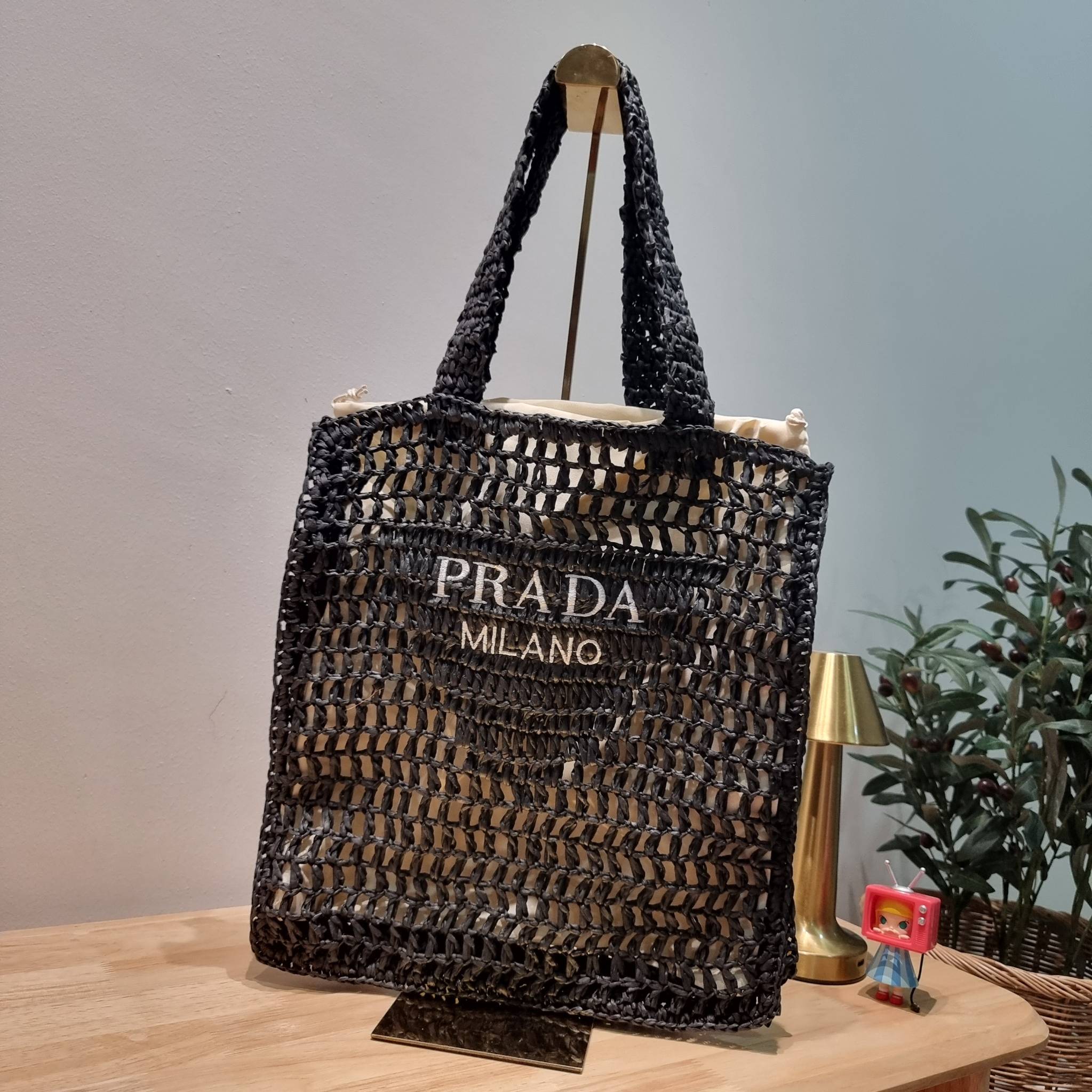 PRADA RAFFIA TOTE BAG สวยไม่ซ้ำใคร สไตล์บีช เหมาะมากกับการสะพายไปเที่ยวทะเล หรือจะใช้ในวันสบายๆก็ตอบโจทย์ กับกระเป๋าสะพายสานใบใหญ่ ตัวกระเป๋าเป็นวัสดุสังเคราห์จากธรรมชาติ