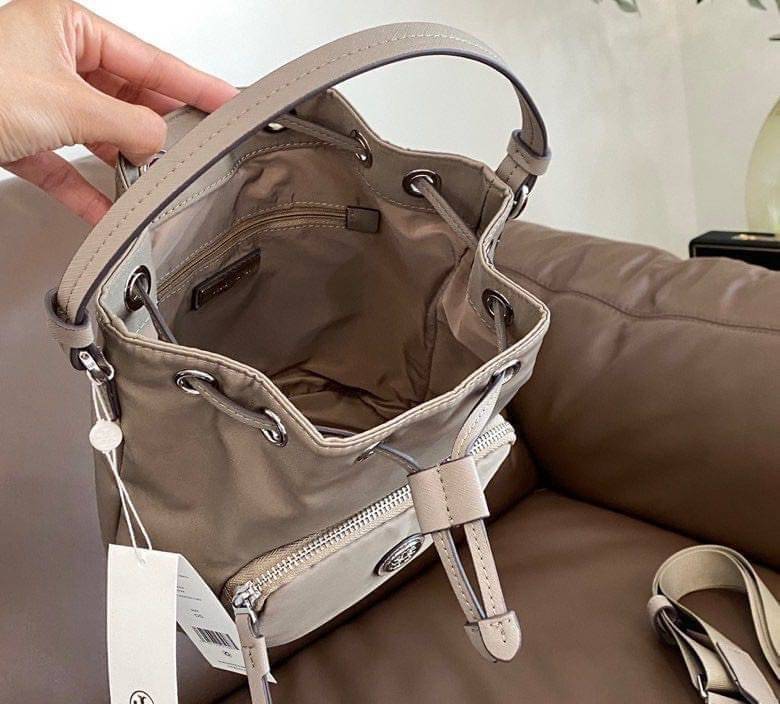 Tory Burch Virginia Nylon Bucket Bag / Tory Burch logo-plaque bucket bag กระเป๋าสะพายทรงบัคเก็ต เปิด-ปิดหนังรูดปากกระเป๋า มีหูหิ้วในตัว คล้องแขนเก๋ๆ ภายในเป็นช่องโล่ง มีช่องย่อย ใส่ของสำคัญจุกจิกได้ มีสายครอส จะสะพายไปไหนก็ได้ทุกโอกาส สวยเลิศทุกสี พร้อมส่