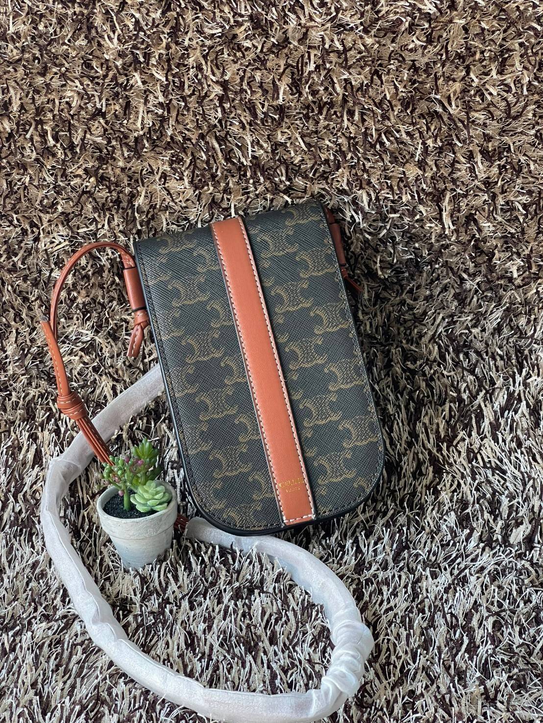 Celine Phone Pouch in Triomphe Canvas กระเป๋าใส่โทรศัพท์รุ่นนี้ มีดีไซน์ดูเรียบง่าย แต่ดูหรูหราด้วยลวดลาย Triompe ที่แสดงถึงความเป็นเอกลักษณ์ของ celine ช่องหลักที่มีความกว้าง สามารถใส่โทรศัพท์มือถือ ธนบัตร บัตรต่าง ๆ และของจุกจิกชิ้นเล็ก ๆ ได้แบบจุใจ หรือ