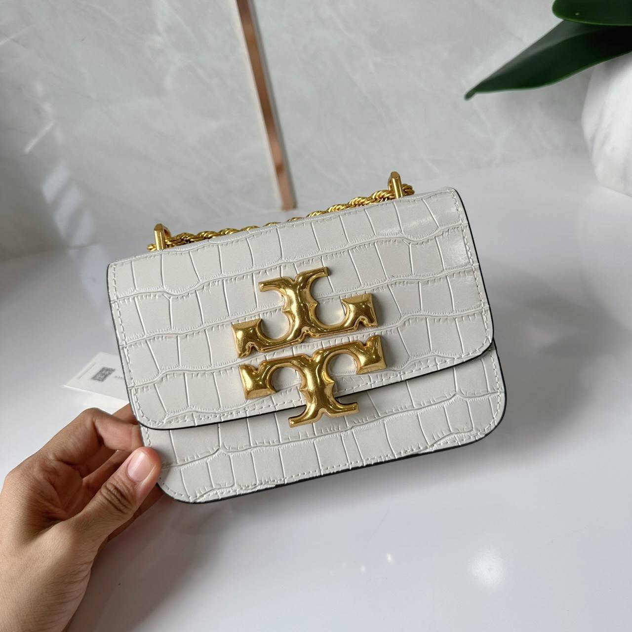 6 สี Tory Burch Croc Eleanor Small Bag / TORY BURCH ELEANOR CROC EMBOSSED LEATHER กระเป๋าสะพายหนังพิมพ์ลายจระเข้ ดีไซน์หรูหรา โด่นเด่นด้วยโลโก้แบรนด์อะไหล่ด้านหน้า และสายสะพายโลหะสีทอง