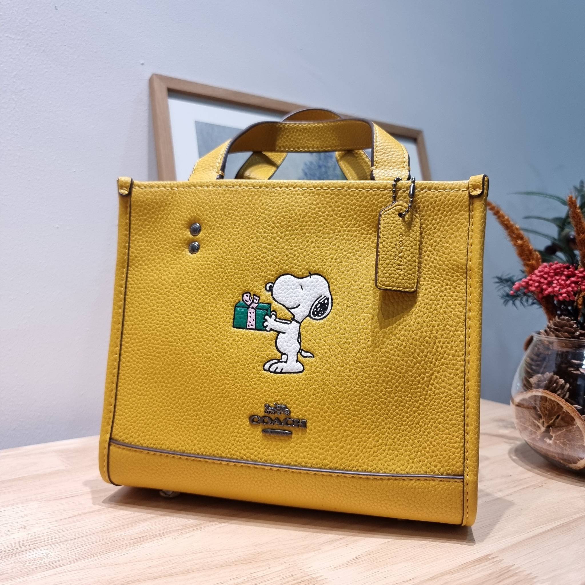 coach x peanuts dempsey tote 22 with snoopy present motif CE918 คอลเลคชั่นใหม่ น้องน่ารักเกินต้านไปมาก!! กับกระเป๋าทรงโท้ท ไซส์กำลังสวย ดีไซน์ ลายการ์ตูนยอดฮิต ที่ใครๆก็ต้องรู้จัก พิมพ์คมชัดลงบนหนัง pepble ผิวสัมน่าใช้ ปากกระเป๋ามีกระดุมแม่เหล็กปิดกันของห