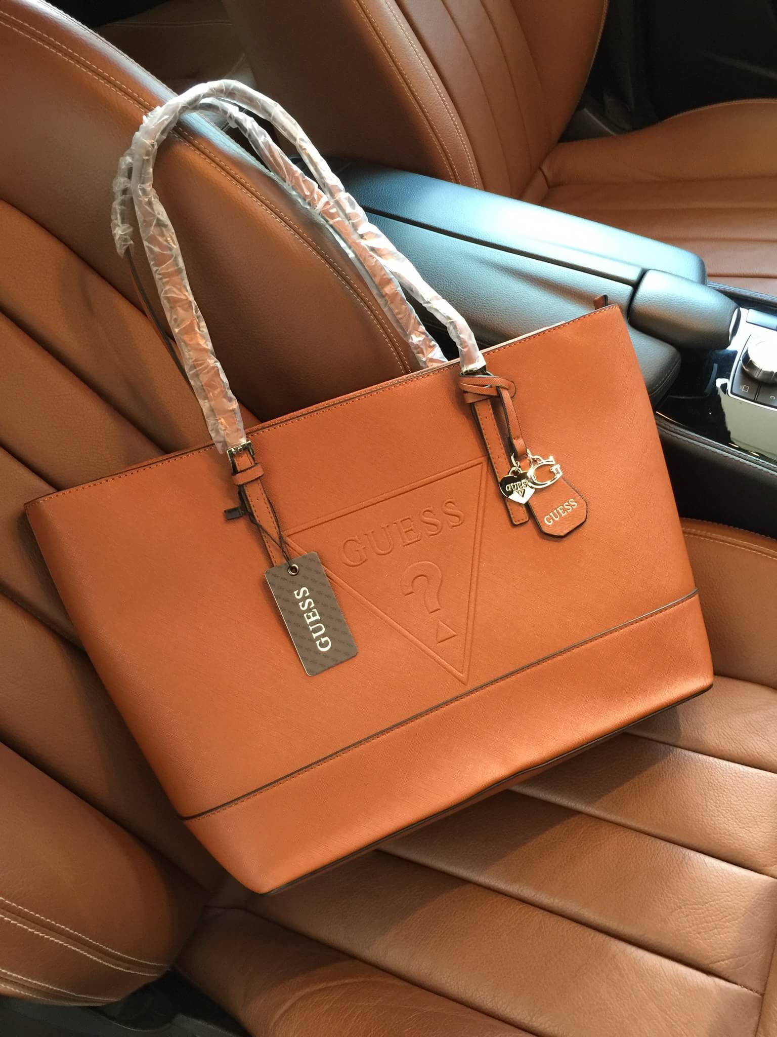 Guess Saffiano Shopping Bag กระเป๋าถือและคล้องบ่าทรงช้อปปิ้งใบใหญ่ หนังSaffiano ใส่เอกสารขนาด A4 ได้ จุของได้เยอะ ด้านหน้าสลักแบรนด์หนังลายนูนพร้อมประดับtagสายหนังถอดออกได้ เปิดปิดด้วยซิปเดียวด้านบน ภายในบุผ้าติดโลโก้ มีช่องเล็กและข่องใส่โทรศัพท์ เรียบง่า