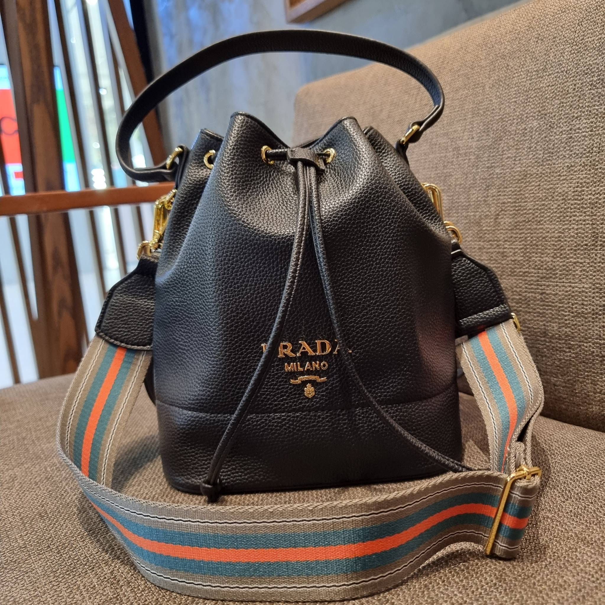 Prada leather bucket bag กระเป๋าสะพายทรงขนมจีบ ดีไซน์เรียบ แต่หรู น่าใช้มากๆ หนังสวยมาก วัสดุหนัง pepble สัมผัสนิ่มมือ ตกแต่งโลโก้สีทองตัดหนังดำ คือเลิศ!! ปากกระเป๋ารูดเปิดปิดได้ สะดวกใช้งาน ภายในโล่งกว้าง จุของได้เยอะ ไม่ธรรมดาเลย พิเศษ!! นอกจากสายคล้องใ