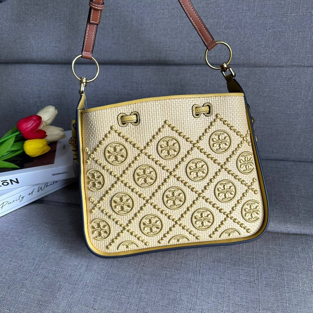 TORY BURCH T Monogram Straw Bell Bag กระเป๋าสะพายข้างรุ่นคลาสสิกที่ได้แรงบันดาลใจจากการควิลท์แบบดั้งเดิมของเพนซิลเวเนีย คอลเลกชันบ่งบอกถึงความมีสไตล์เหนือกาลเวลา รูปทรงเรียวโดดเด่น ปักทอลายแบรนด์อย่างสวยงาม เปิด ปิดด้วยเชือกรูด ด้านในช่องโล่งกว้าง ซับในผ้