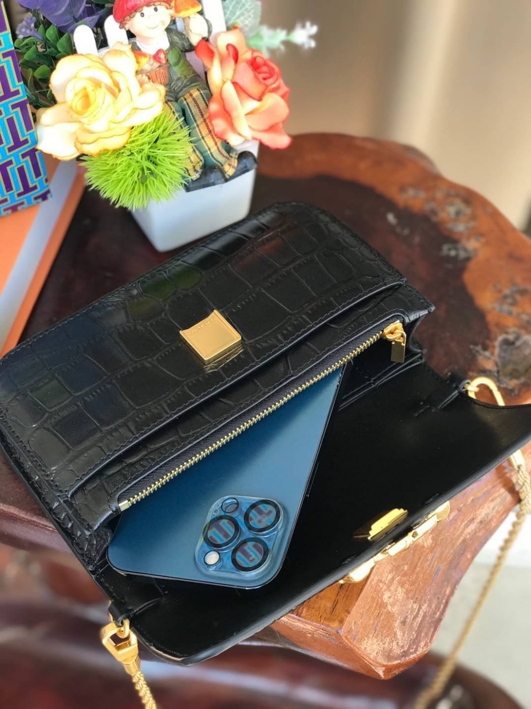 Tory Burch Eleanor Crocodile-Embossed Phone Crossbody Bag จุดเด่นของรุ่นนี้คือดีไซน์ออกมาในสไตล์คลาสสิกที่มาพร้อมกับฮาร์ดแวร์ที่ทำจากวัสดุทองเหลืองและสายสะพายโซ่เกลียวสีทอง ซึ่งการออกแบบได้รับแรงบันดาลใจมาจากเครื่องประดับ รูปทรงกะทัดรัดจึงสามารถสะพายใช้งา