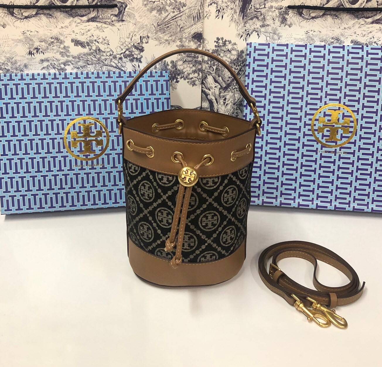 Mini : Tory Burch T Monogram Chenille Bucket Bag เปิดตัวอีกหนึ่งรุ่นกับกระเป๋าลาย T MONOGRAM รุ่นใหม่ล่าสุดจาก TORY BURCH พลาดไม่ได้กับโลโก้สุดคลาสสิก ลวดลาย T Monogram คือวัสดุ chenille หรือที่เรียกว่า ด้านไหมกำมะหยี่ มารังสรรค์ลงบนกระเป๋าBucketใบนี้ เป็